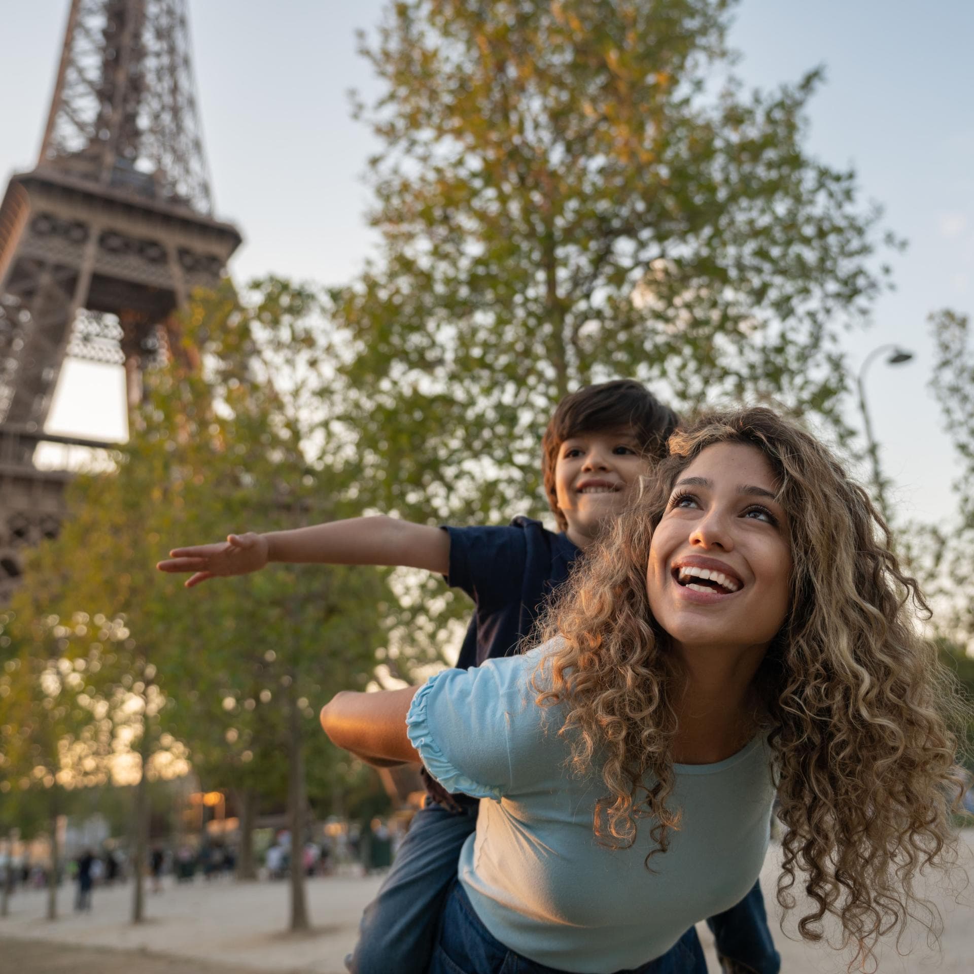 Eine Mutter und ihr Sohn spielen vor dem Eiffelturm in Paris, Frankreich. 