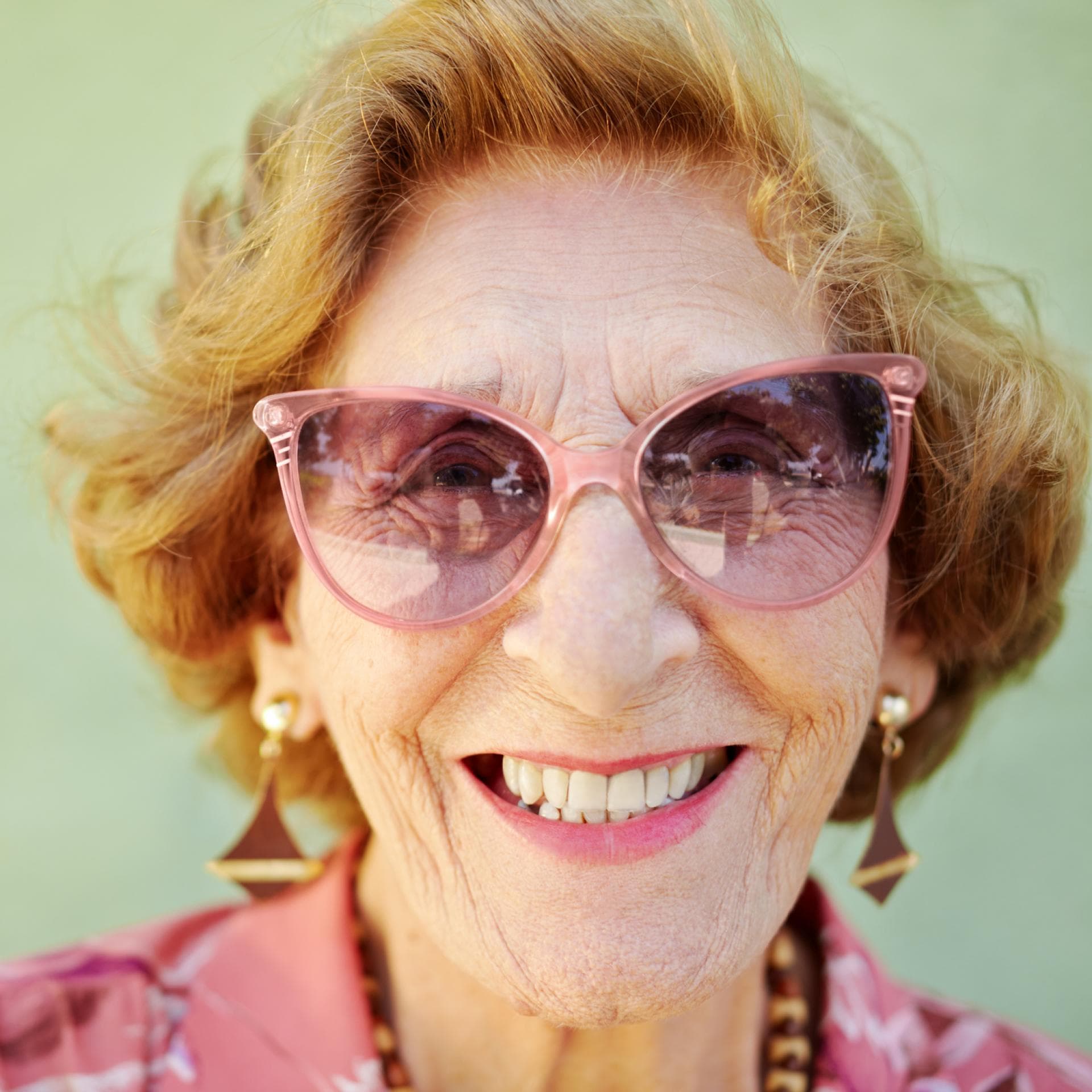 Lachende alte Frau mit rosa Sonnenbrille.