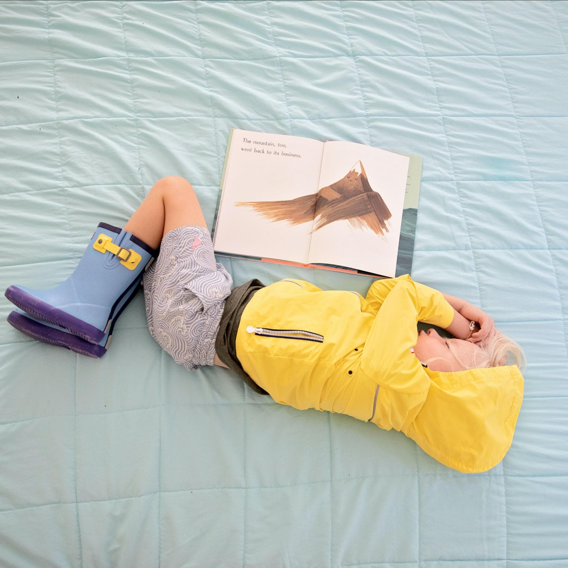 Ein Kind in Regenkleidung beim Lesen eingeschlafen