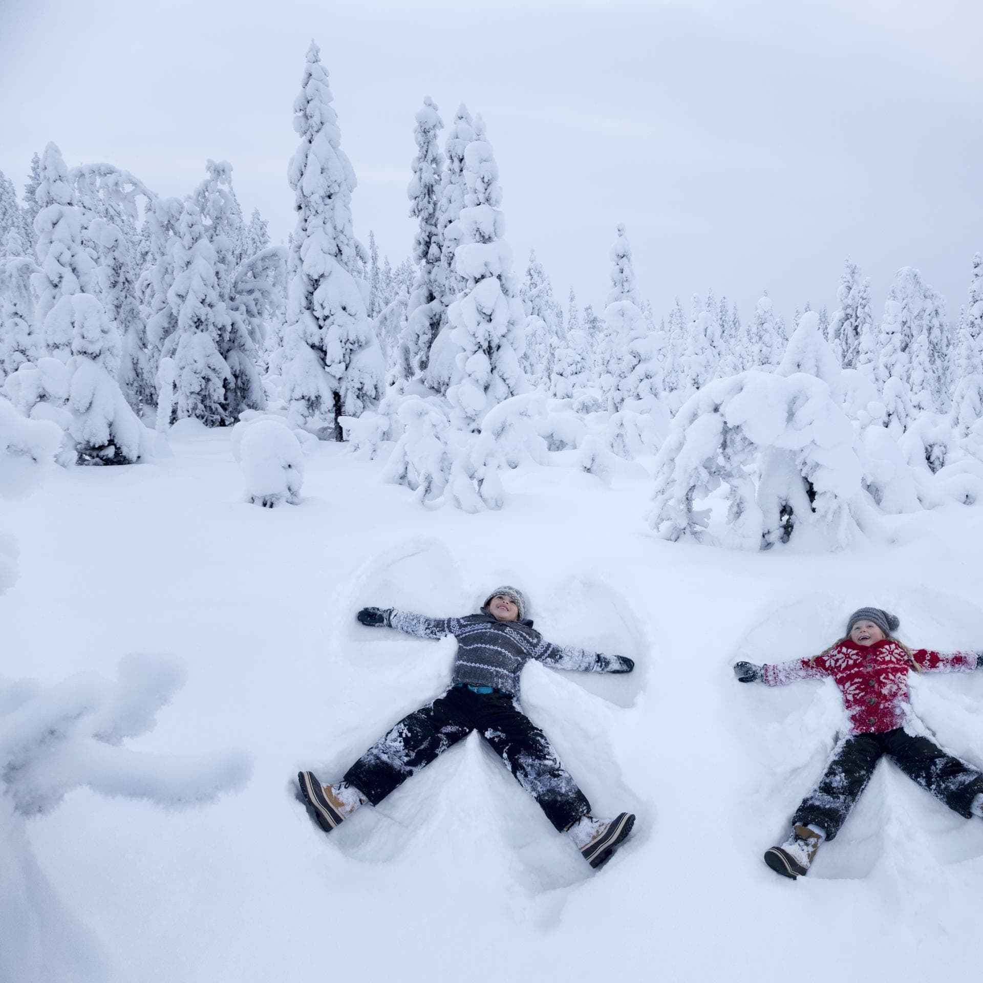 Zwei Kinder machen Schneeengel.
