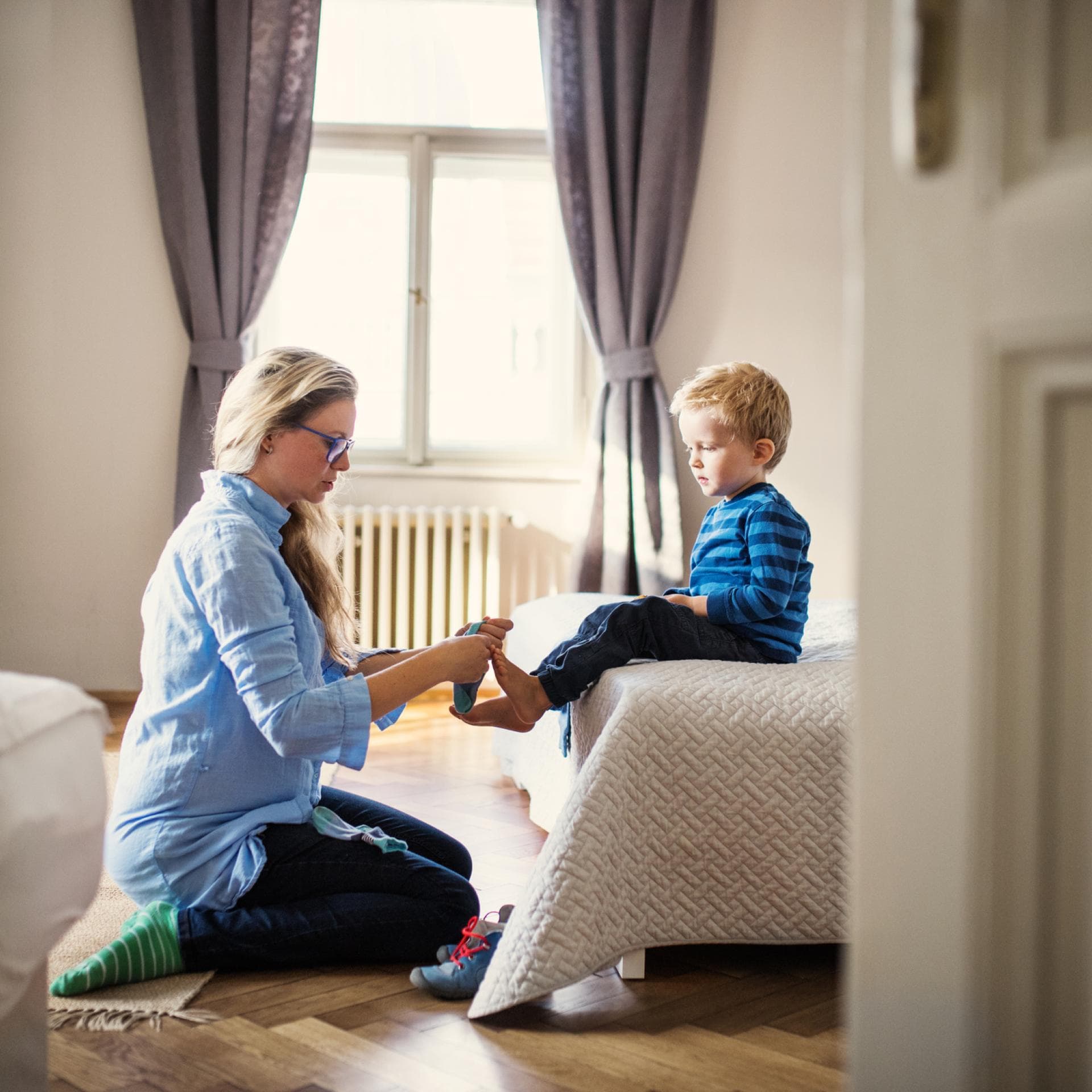 Mutter zieht ihrem Sohn die Socken an.
