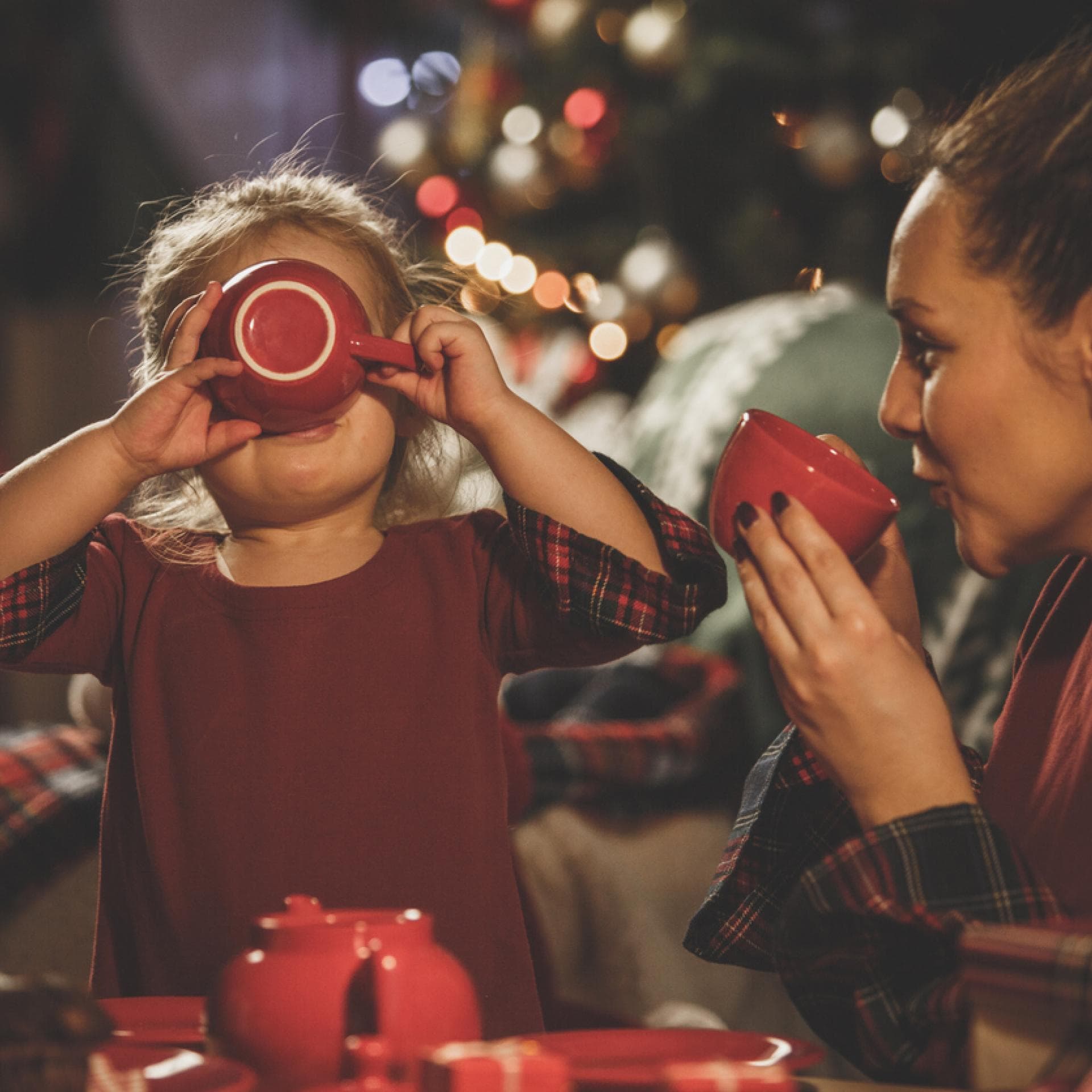Kleines Mädchen trinkt mit ihrer Mama alkoholfreien Kinderpunsch zur Weihnachtszeit.