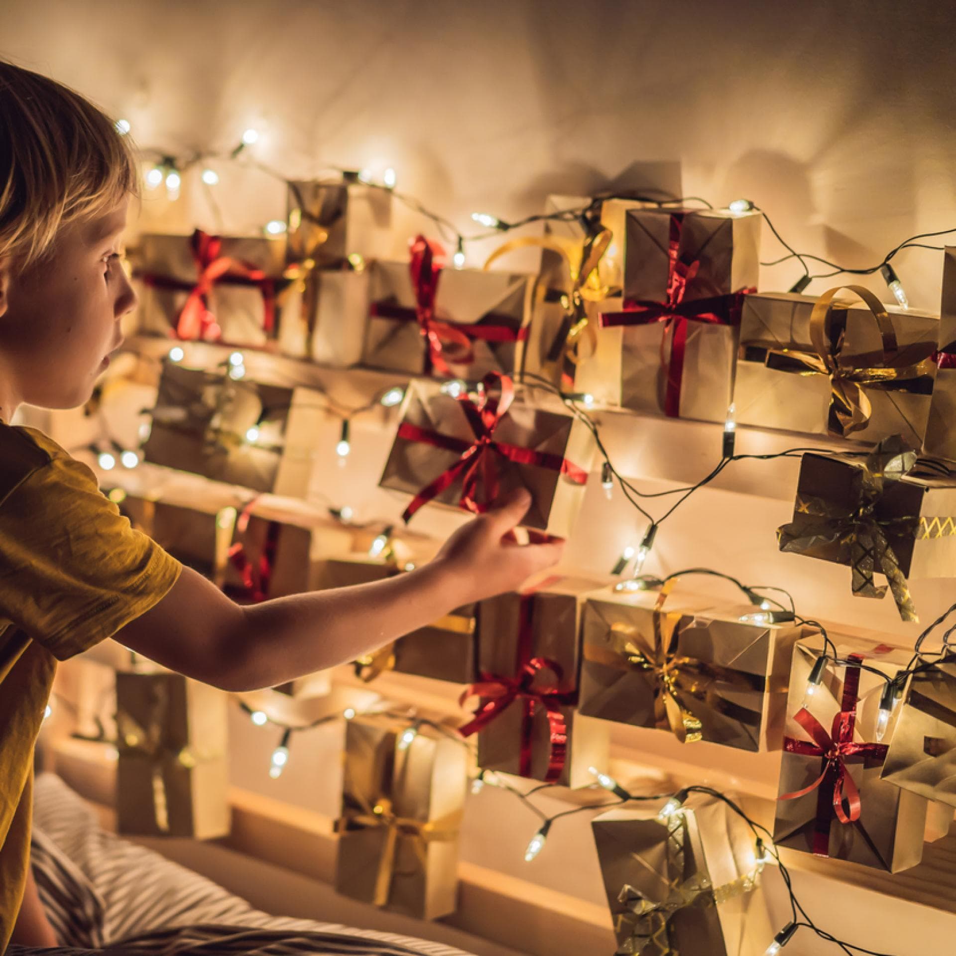 Ein kleiner Junge öffnet ein Türchen seines Adventskalenders. 