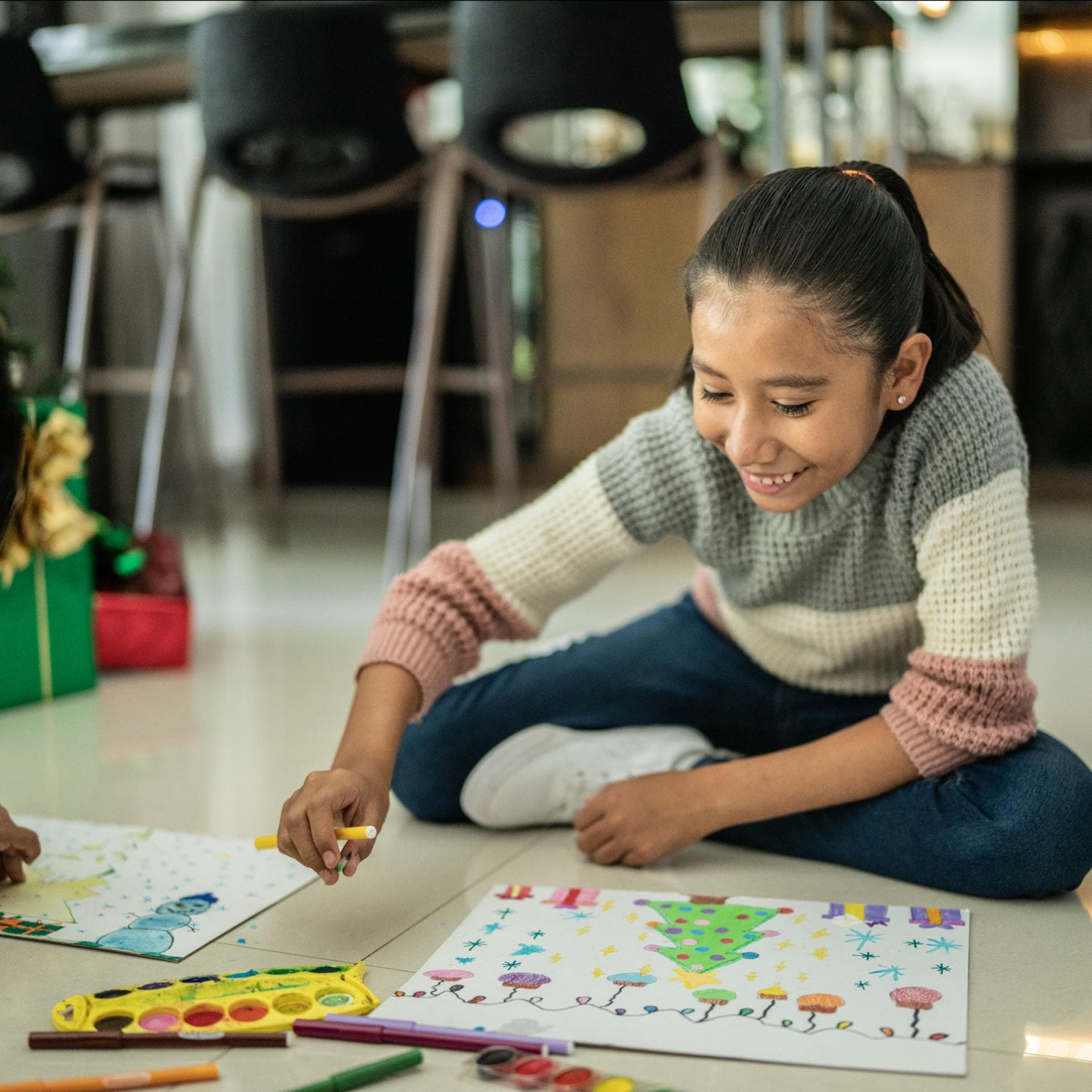 Geschwister malen zusammen Weihnachtsbilder auf dem Boden bunt aus.