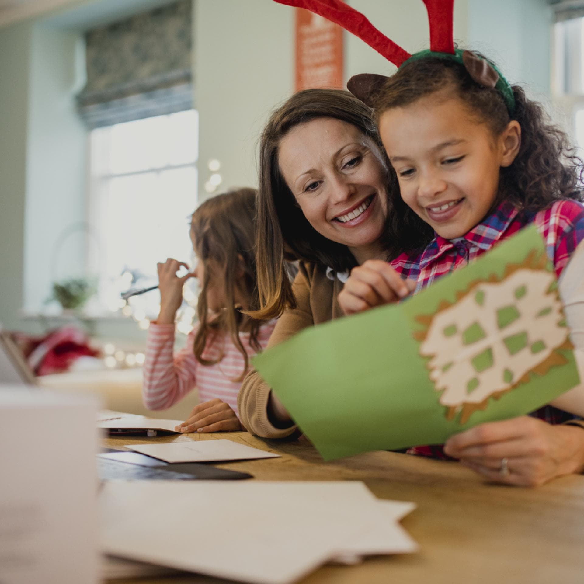 Mutter liest ihrer Tochter eine Karte mit Weihnachtsgrüßen vor.