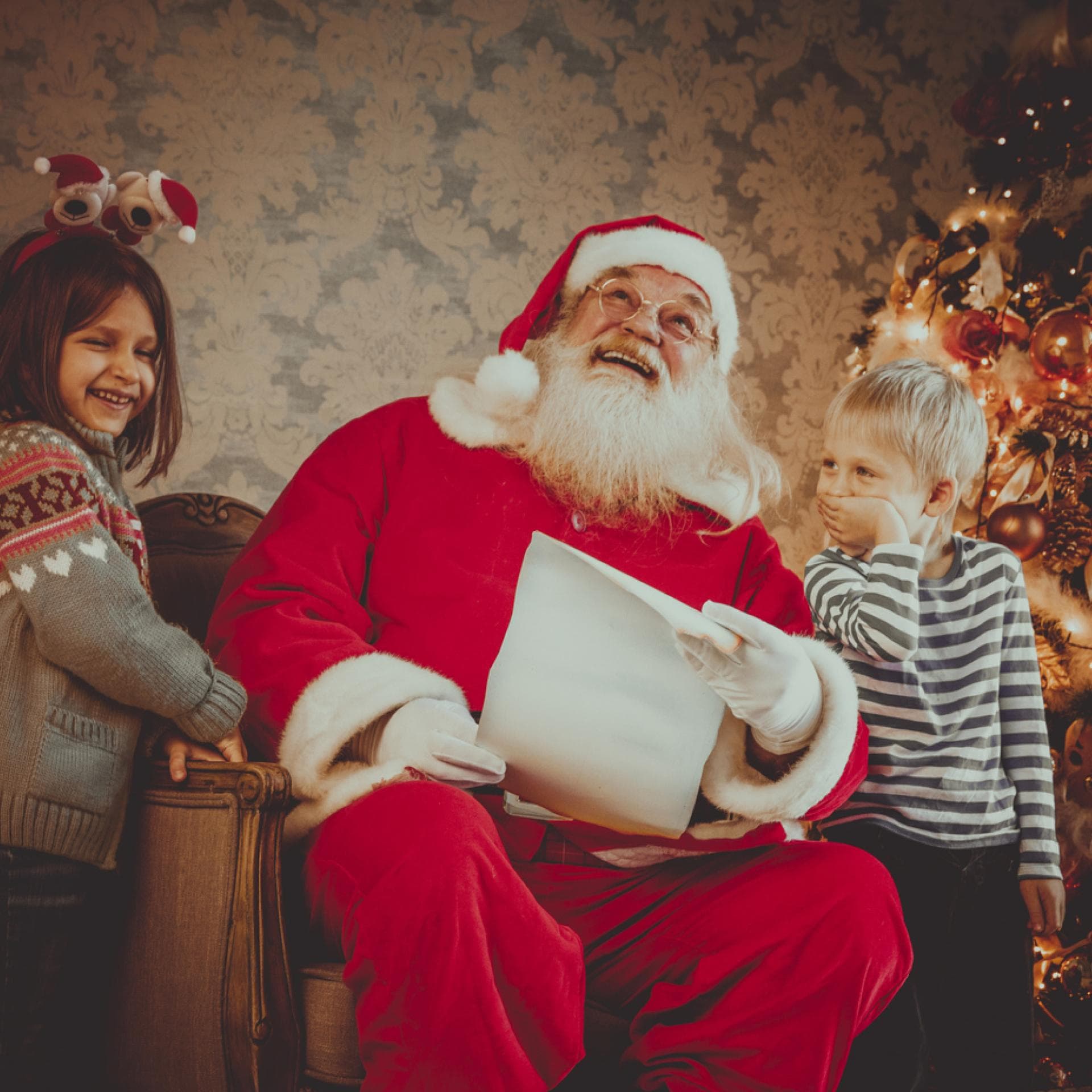 Nikolaus mit zwei Kindern lachen über einen lustigen Nikolausspruch.
