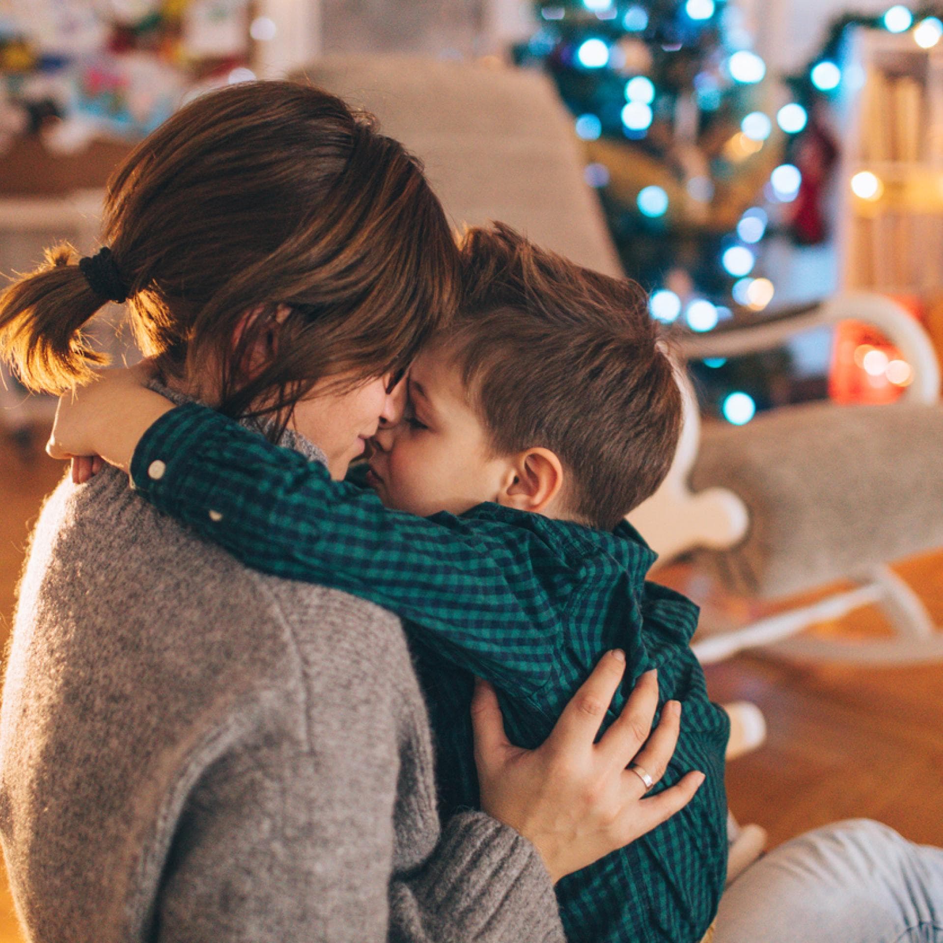 Kleiner Junge kuschelt mit seiner Mama, nachdem sie seine Weihnachtswünsche gelesen hat.