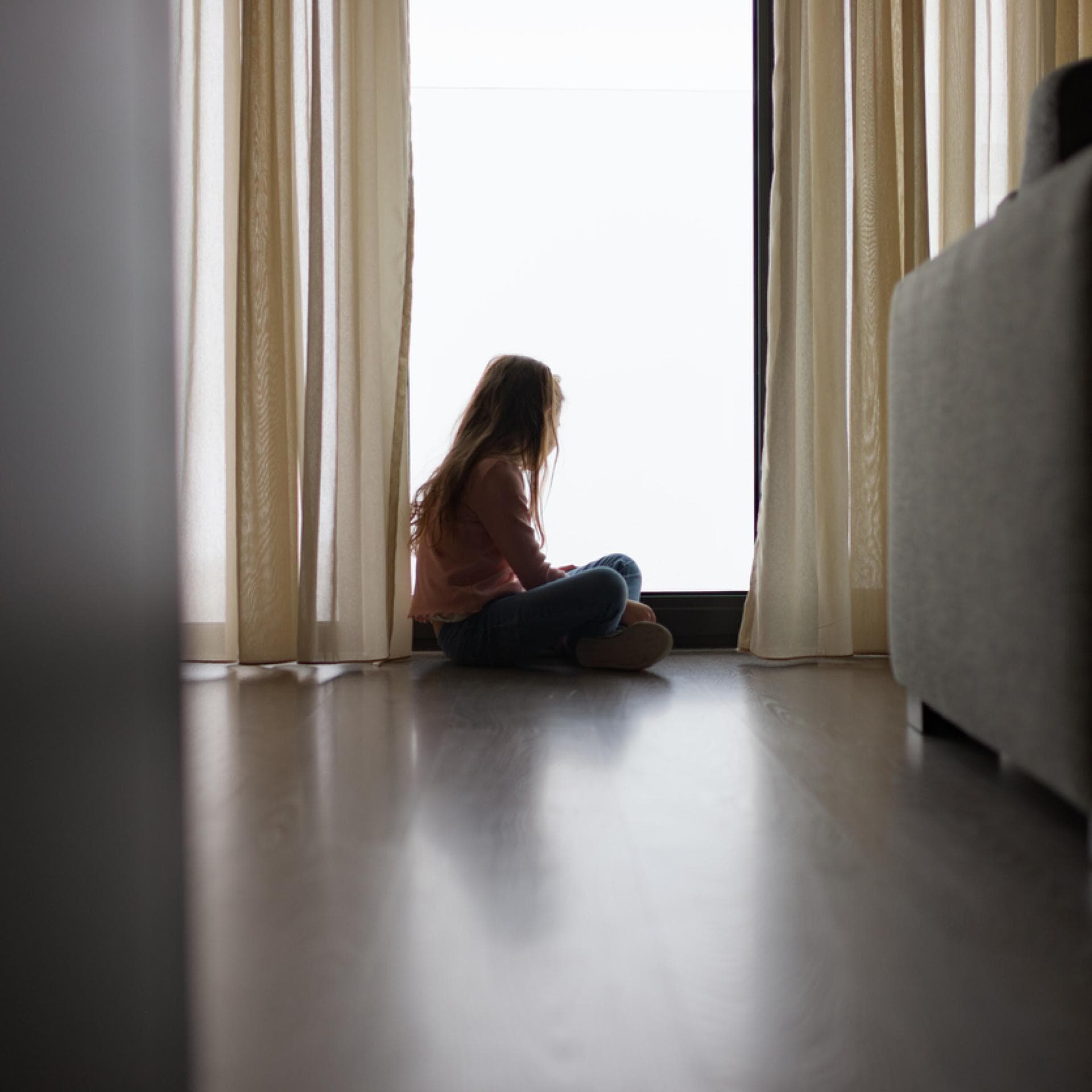 Ein Kind sitzt allein am Fenster