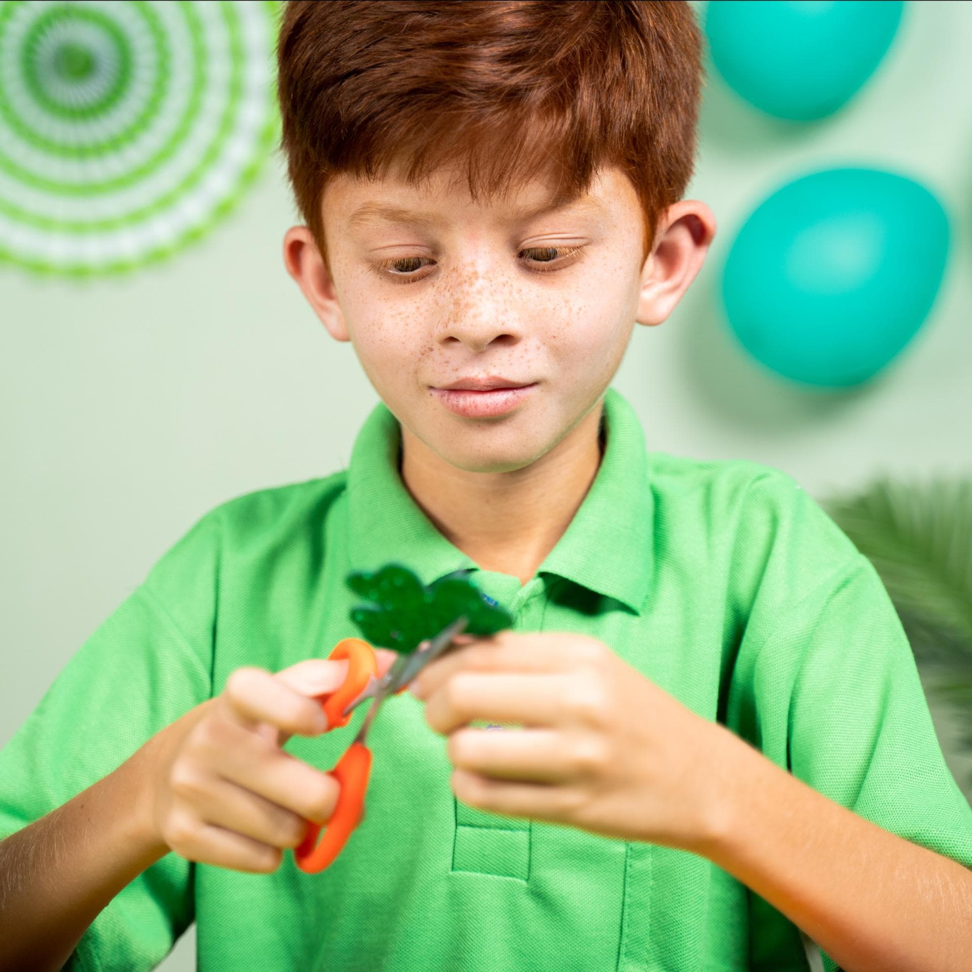 Junge bastelt Kleeblatt als Glücksbringer.