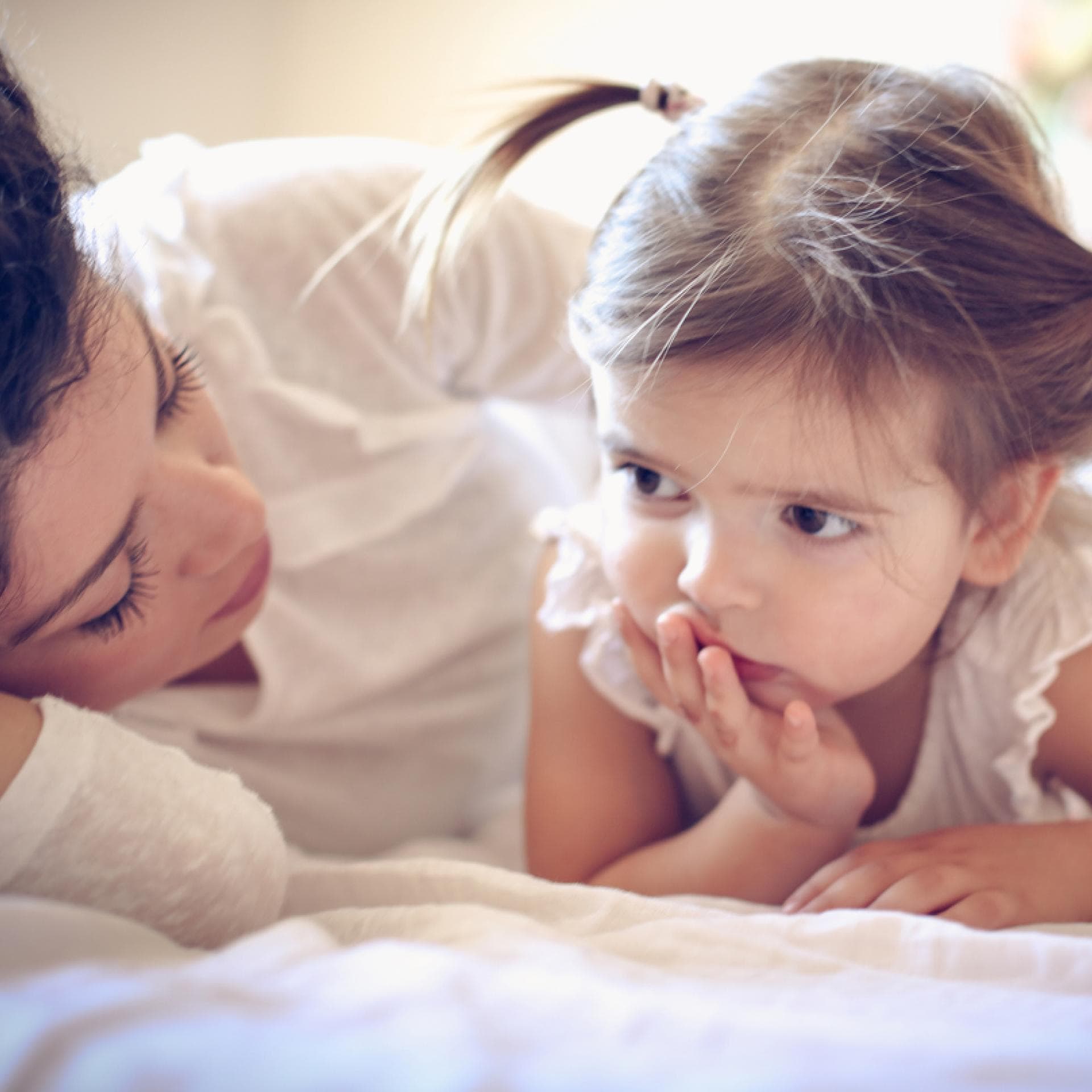 Mutter und Tochter kuscheln im Bett.