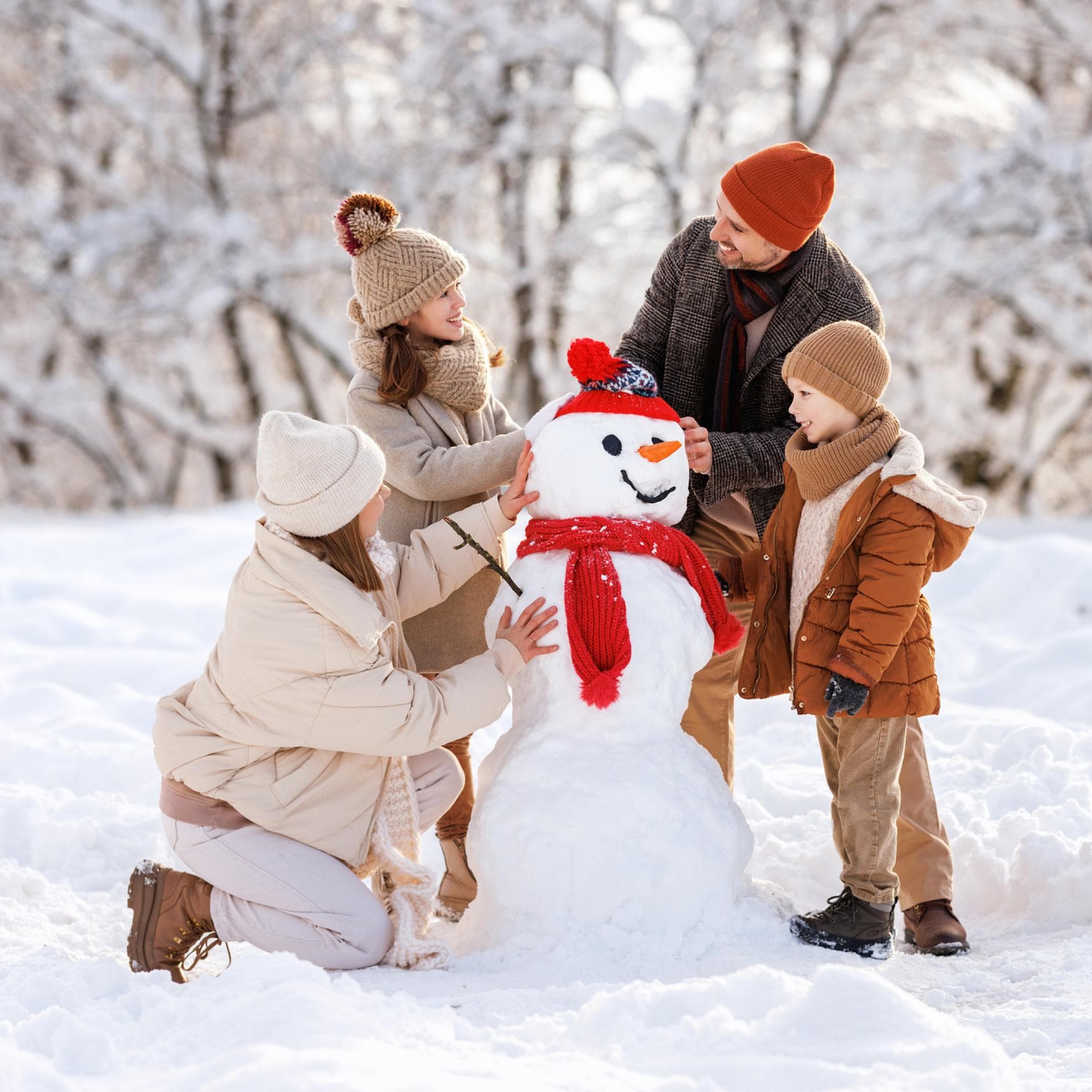 Eine vierköpfige Familie baut einen Schneemann.