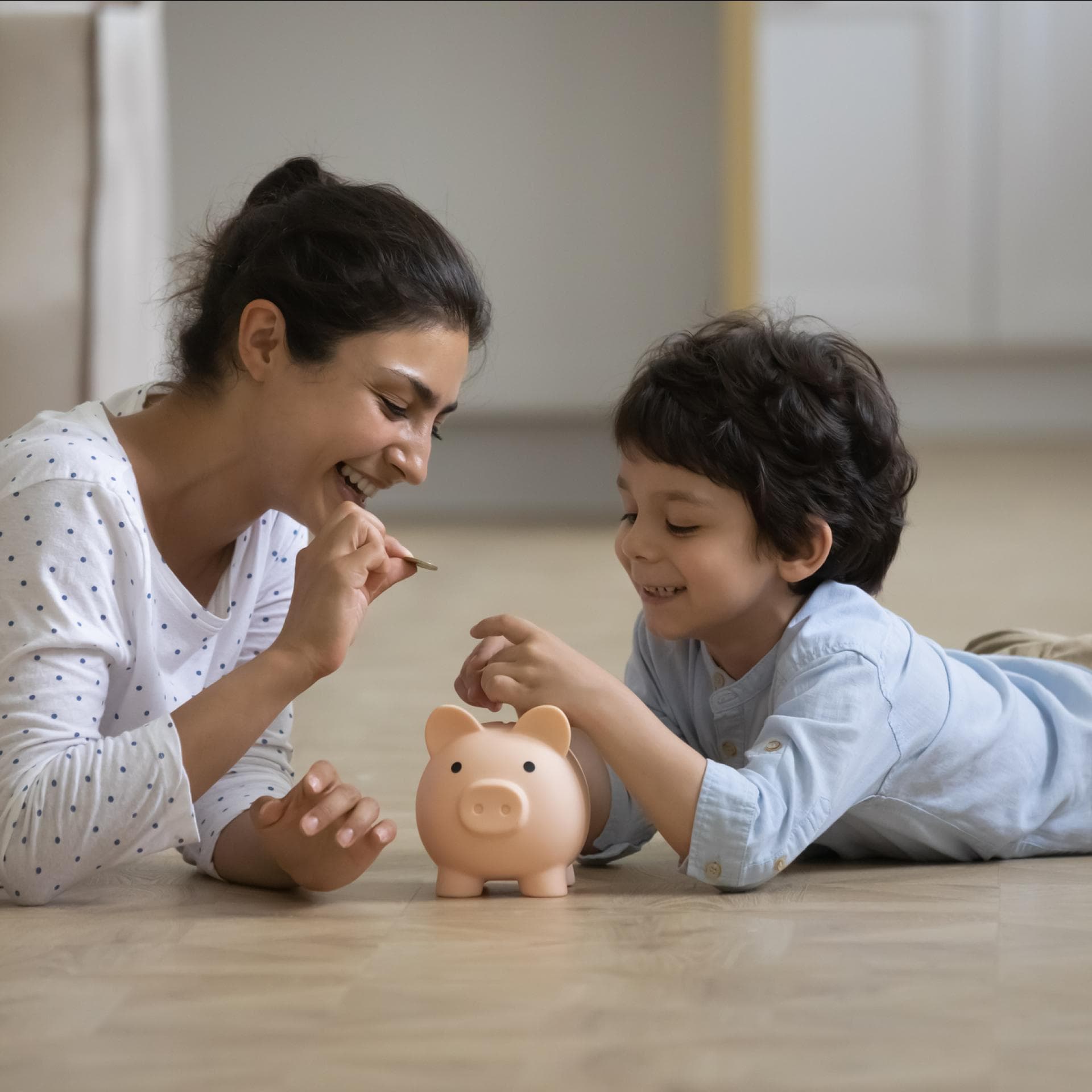 Mutter steckt mit kleinem Jungen Geld ins Sparschwein.