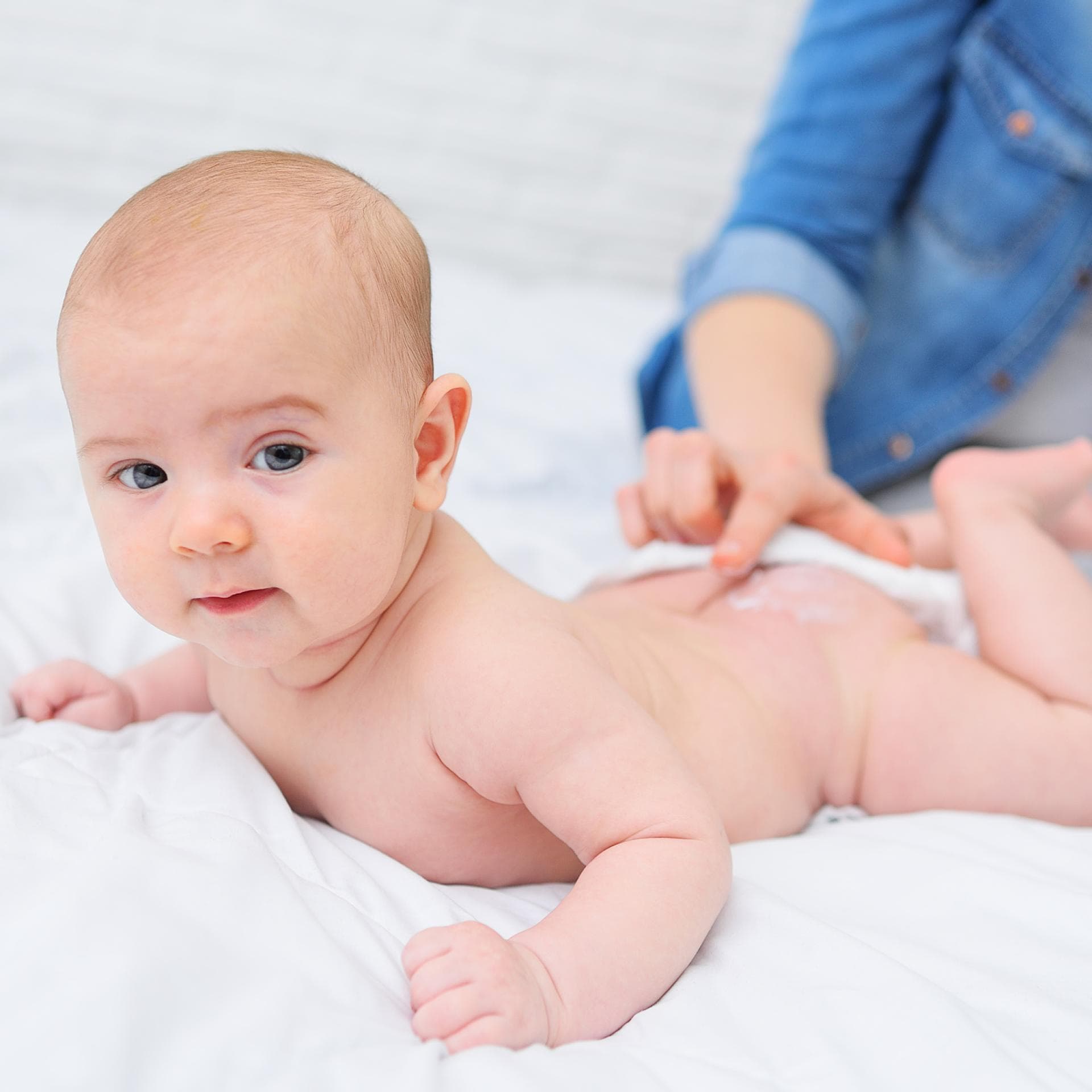 Eine Mama cremt ihrem Baby den Po ein.