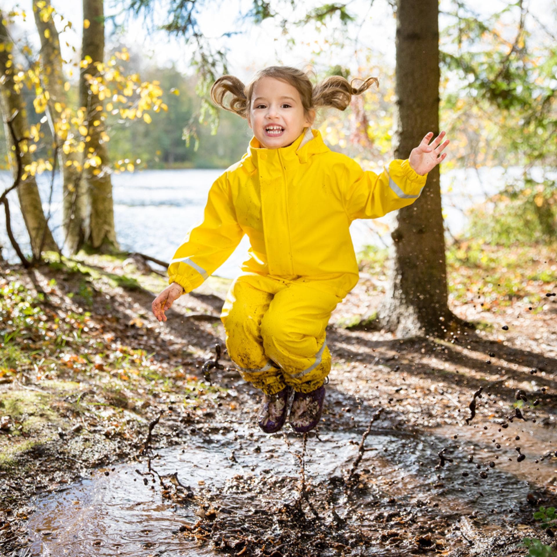 Kind spielt draußen und springt in Pfütze