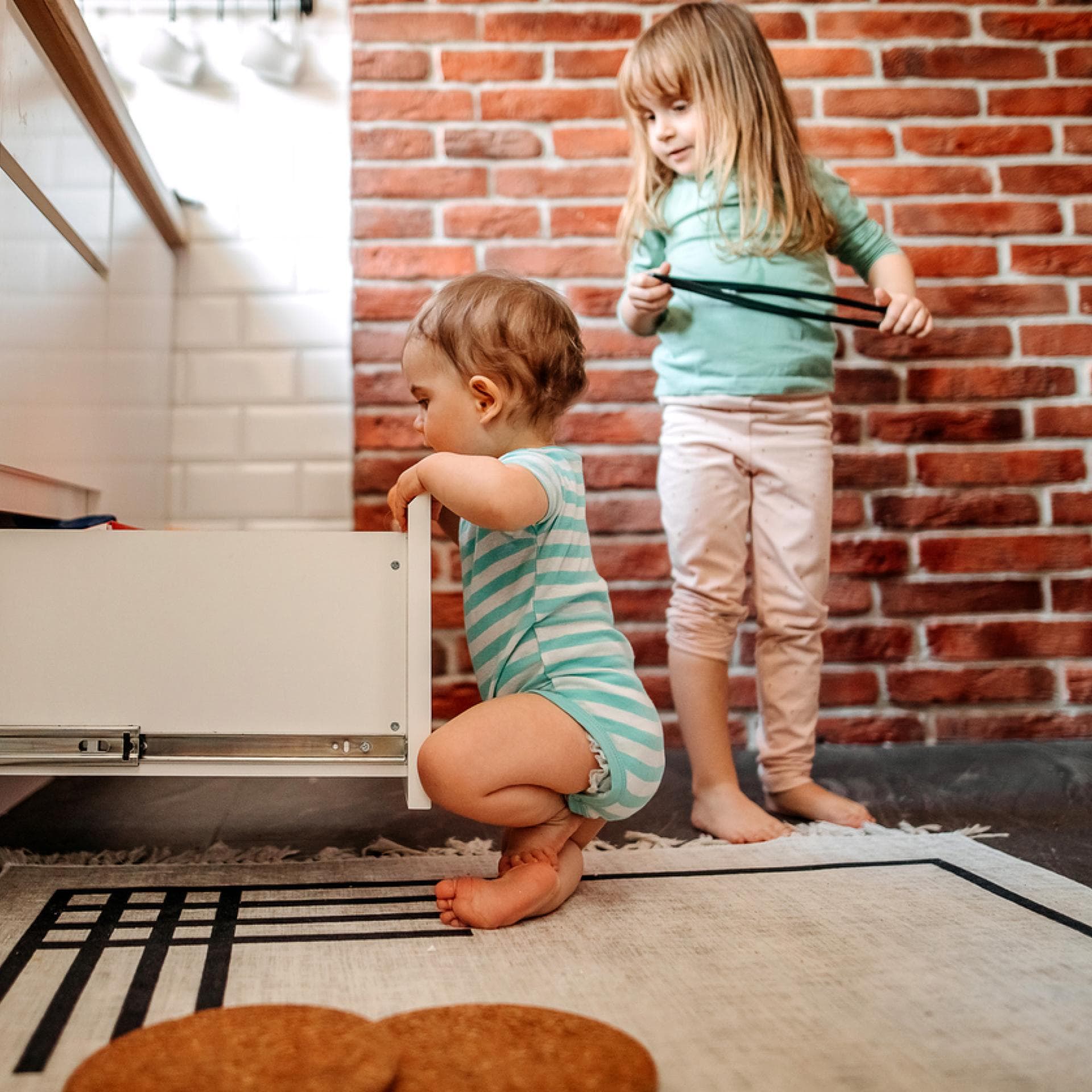 Zwei kleine Kinder schauen nach Süßigkeiten in der Ja-Schublade.
