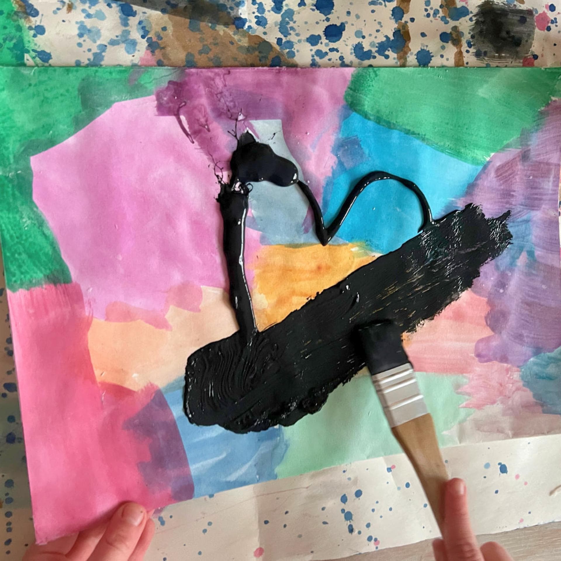 Bunt getuschtes Papier wird mit einer schwarzen Schicht Acrylfarbe übermalt