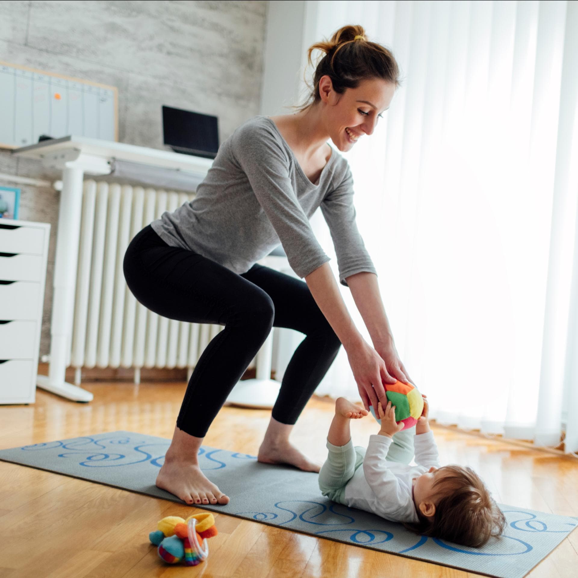 Eine Mutter trainiert ihren Beckenboden, während ihr Baby vor ihr liegt.