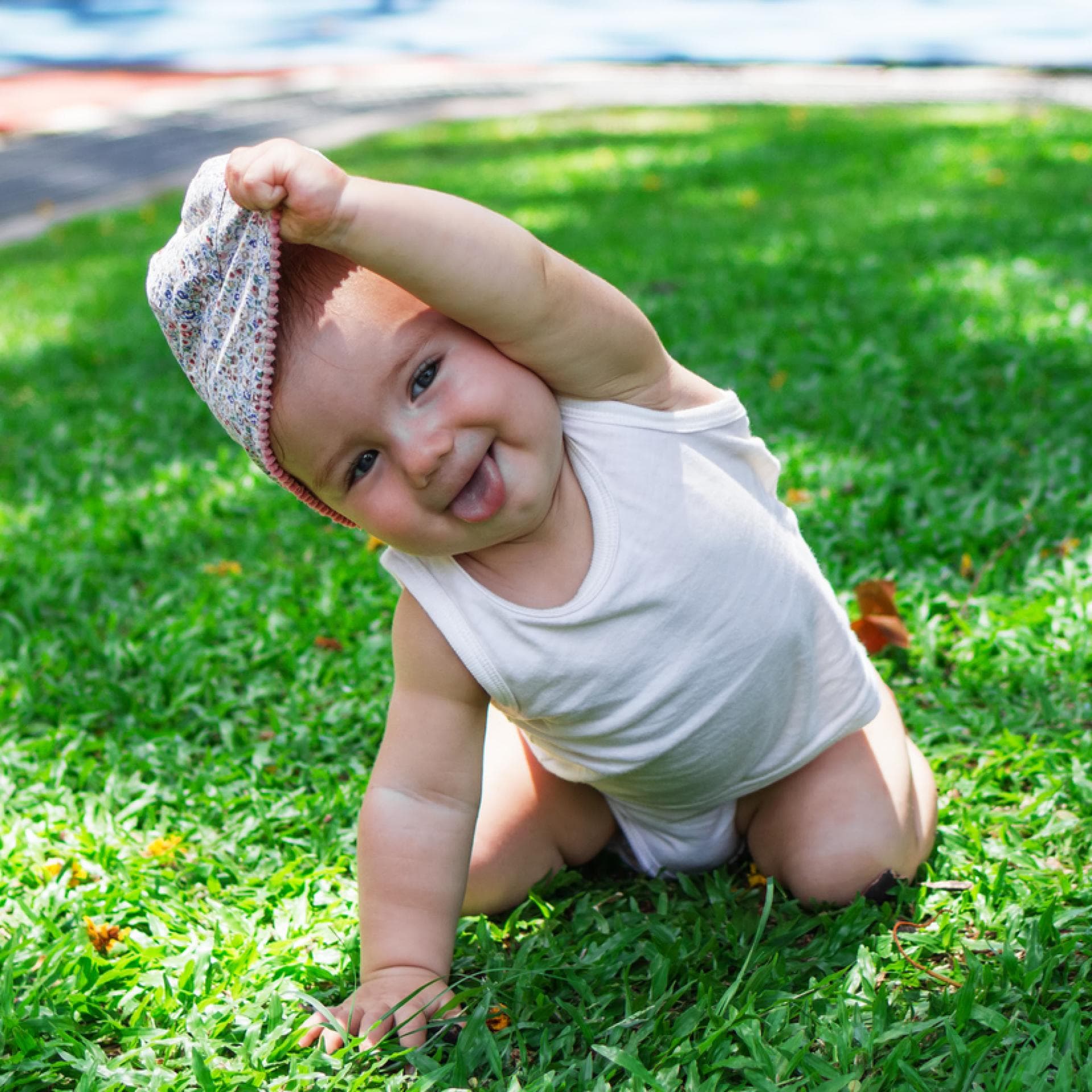 Ein kleines Baby, das sich die Mütze vom Kopf zieht.