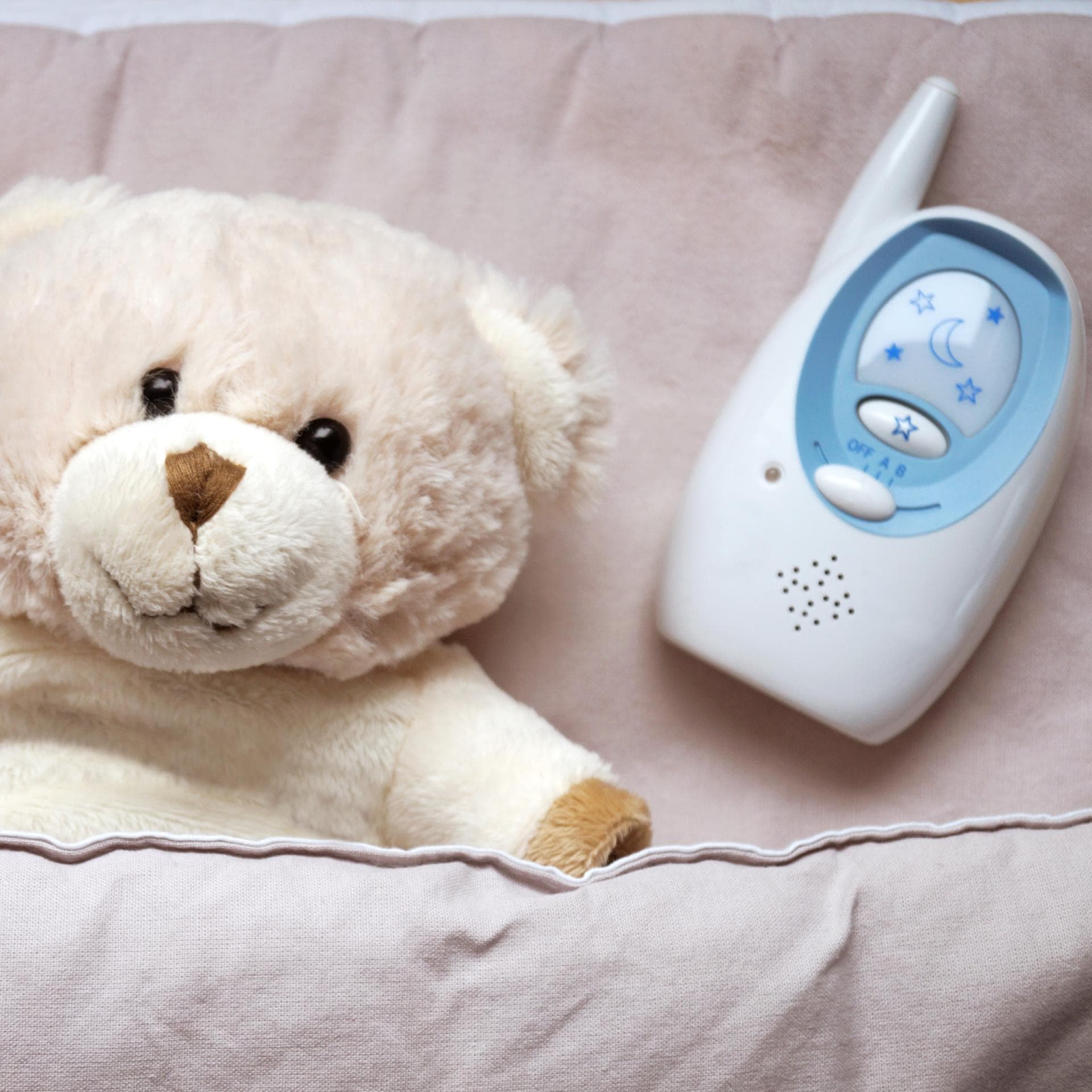 Ein Teddy liegt neben einem Babyphone. 