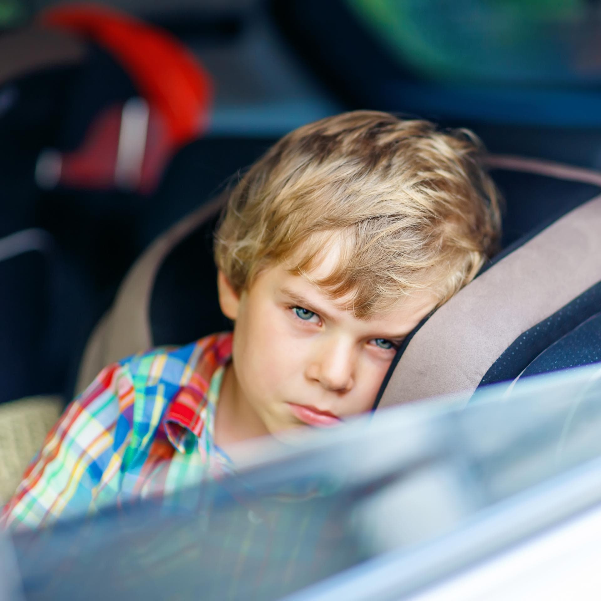Ein kleiner Junge schaut aus dem offenen Autofenster. 