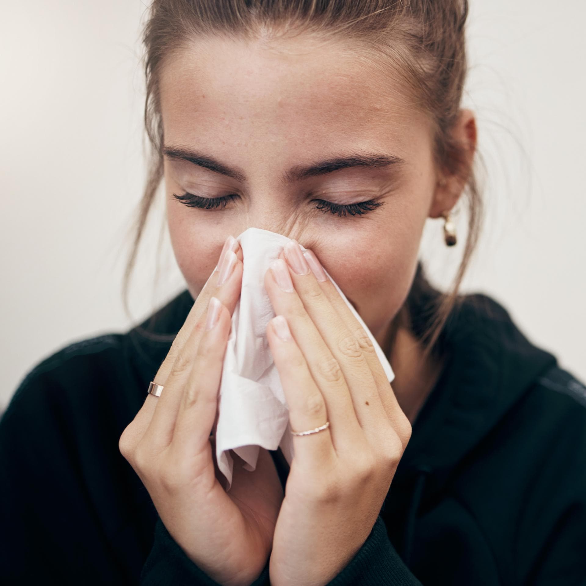 Frau putzt sich die Nase.