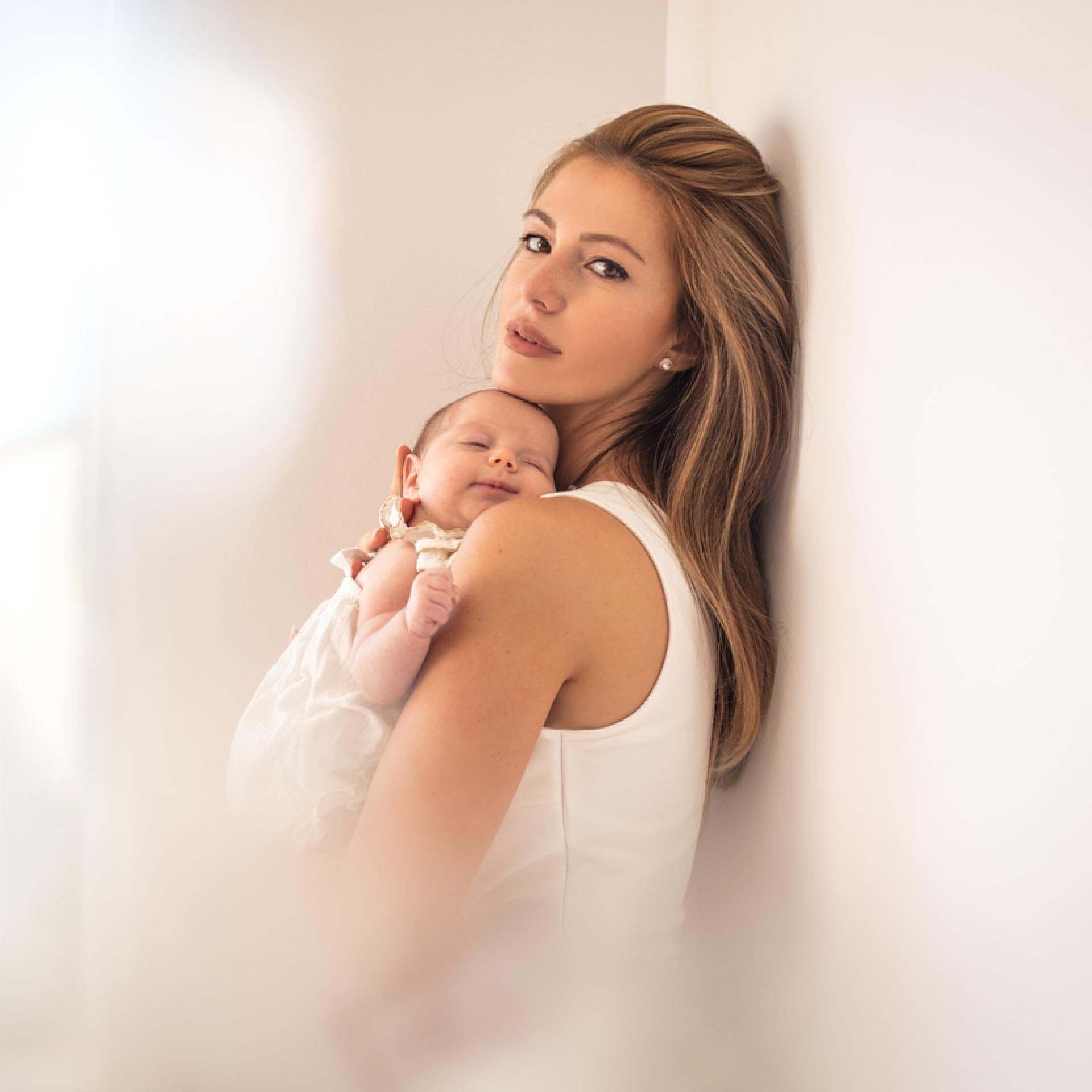 Mutter mit Baby im Arm schaut in den Spiegel.