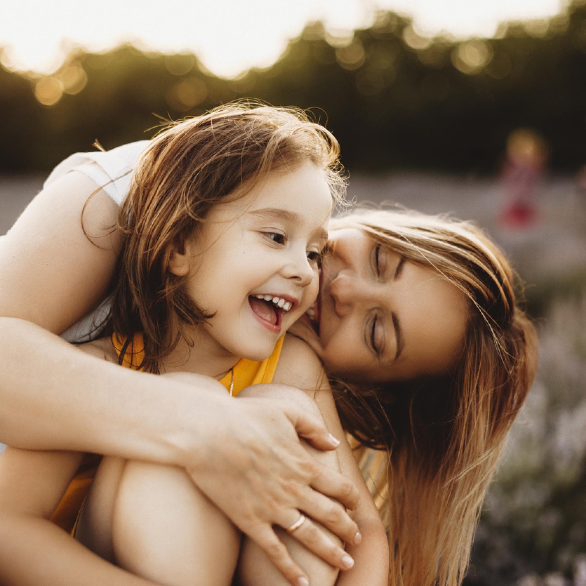 Mutter umarmt ihre Tochter auf der Wiese.