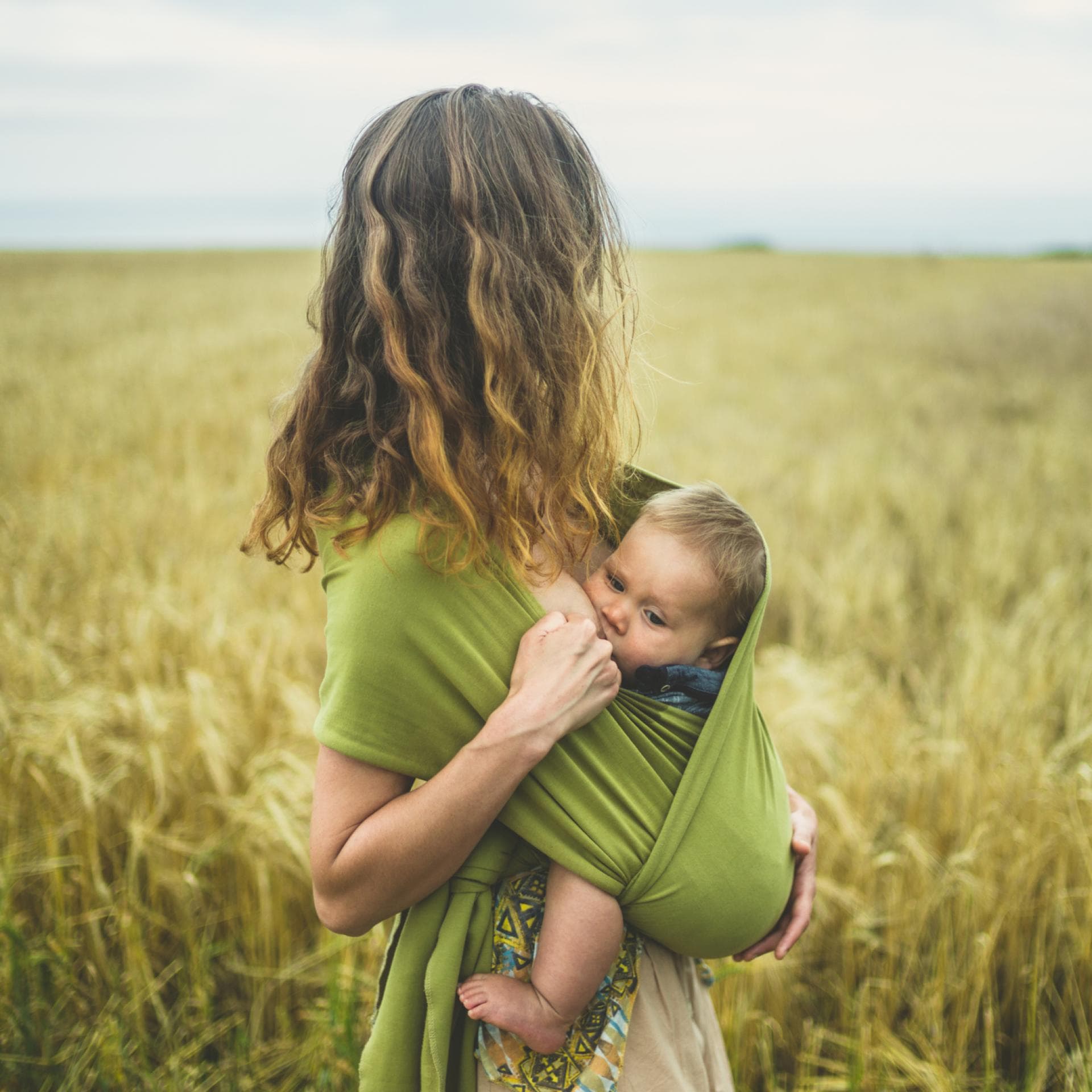 Eine Mama stillt ihr Baby im Tragetuch.