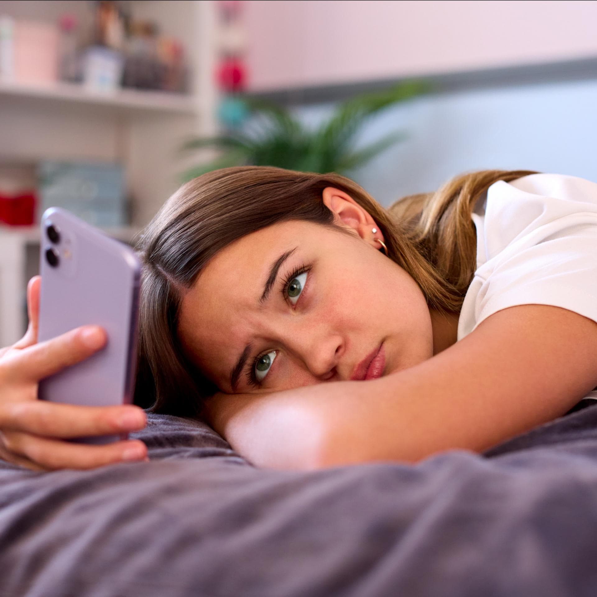 Trauriges Teenager-Mädchen schaut auf ihr Smartphone.