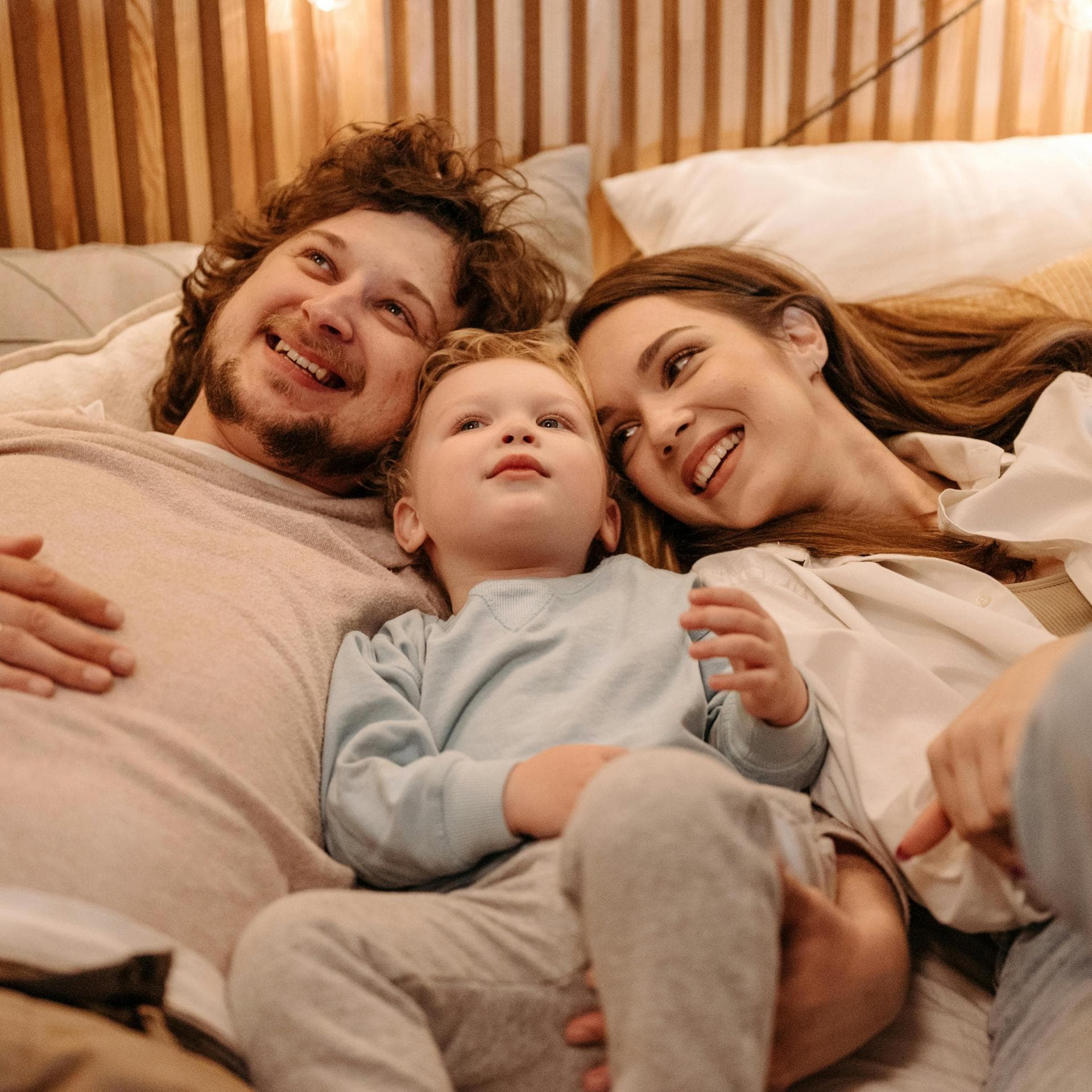 Glückliche Familie liegt gemeinsam im Bett.