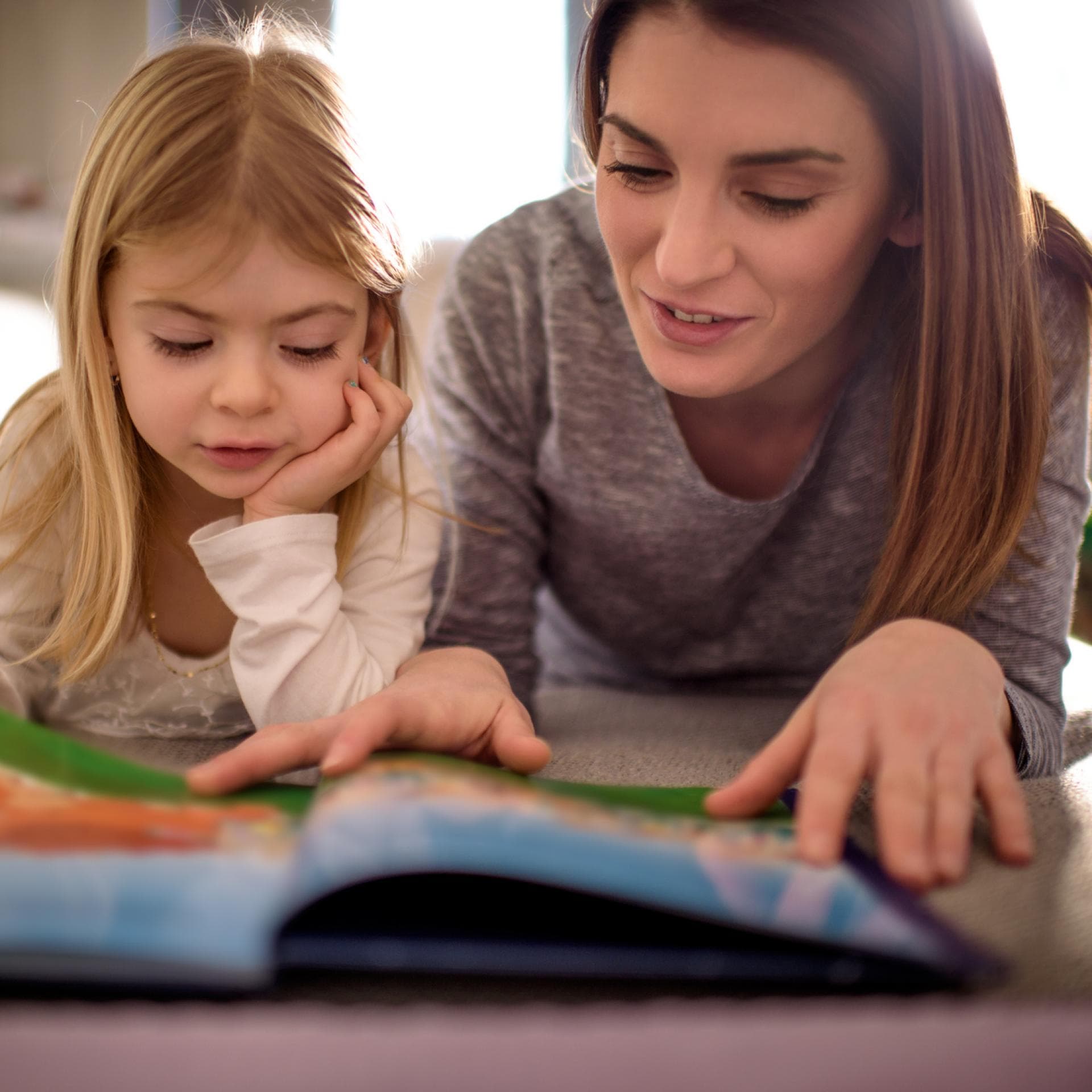 Mutter und Kind lesen gemeinsam auf dem Fußboden.