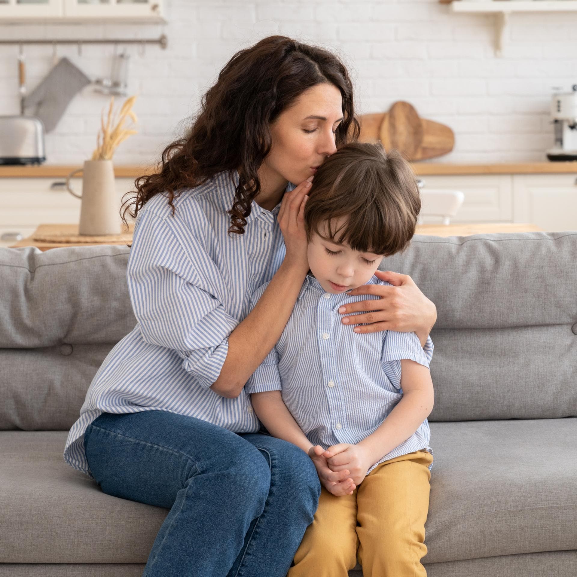 Mutter umarmt Sohn auf dem Sofa.
