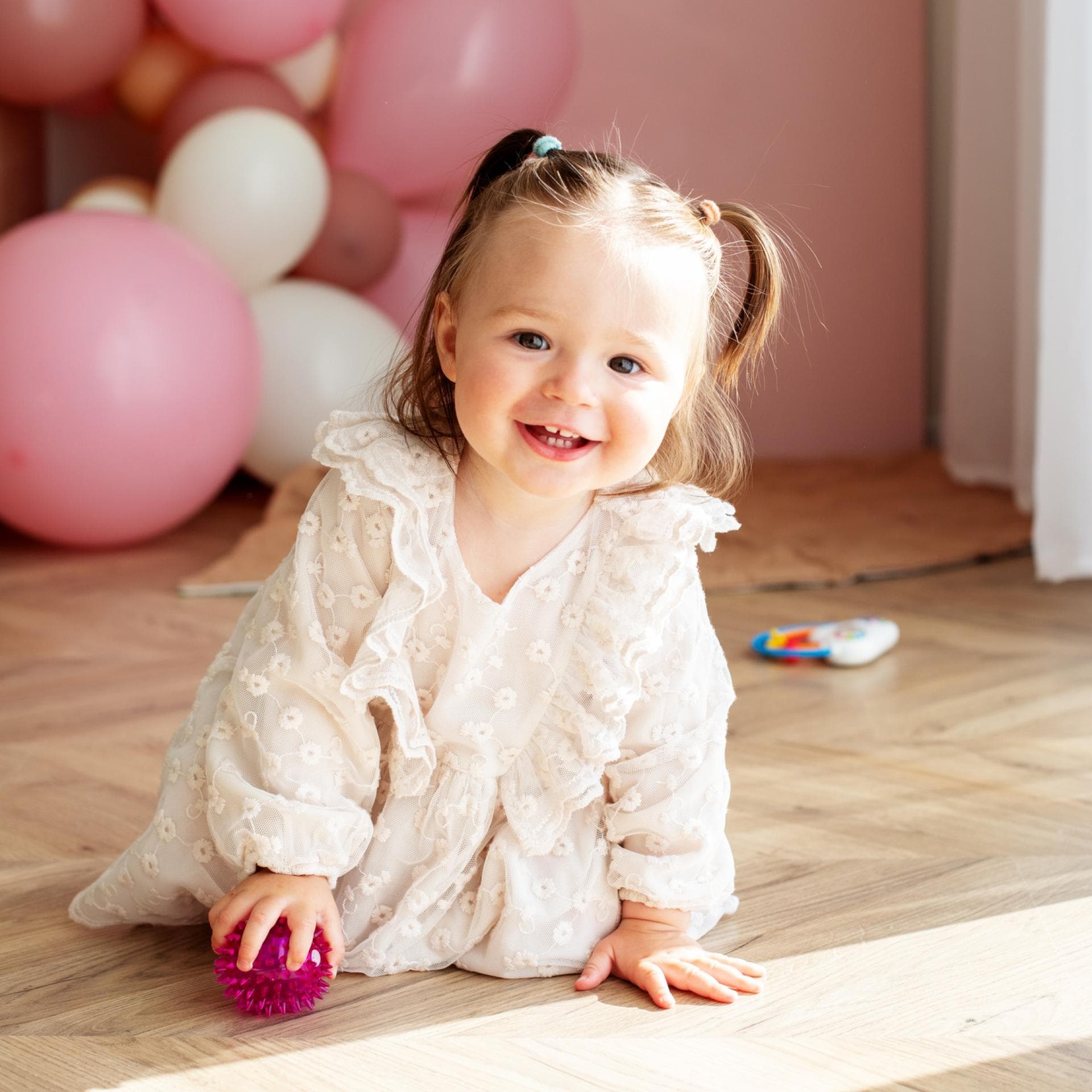 Lachendes Mädchen in Kleid mit rosa Luftballons.