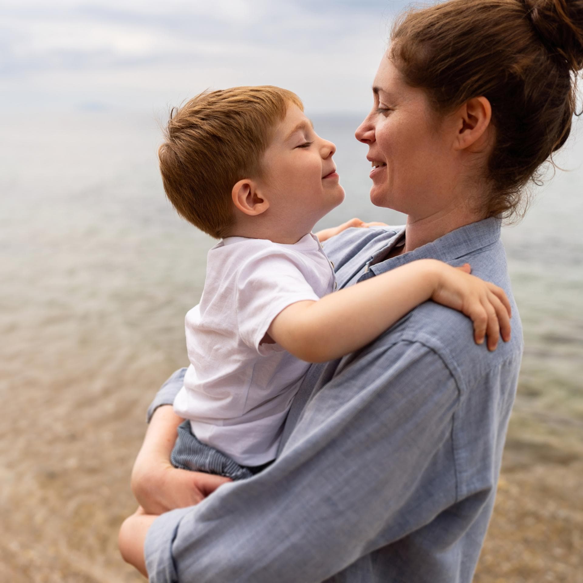 Mutter hält Sohn am Strand im Arm