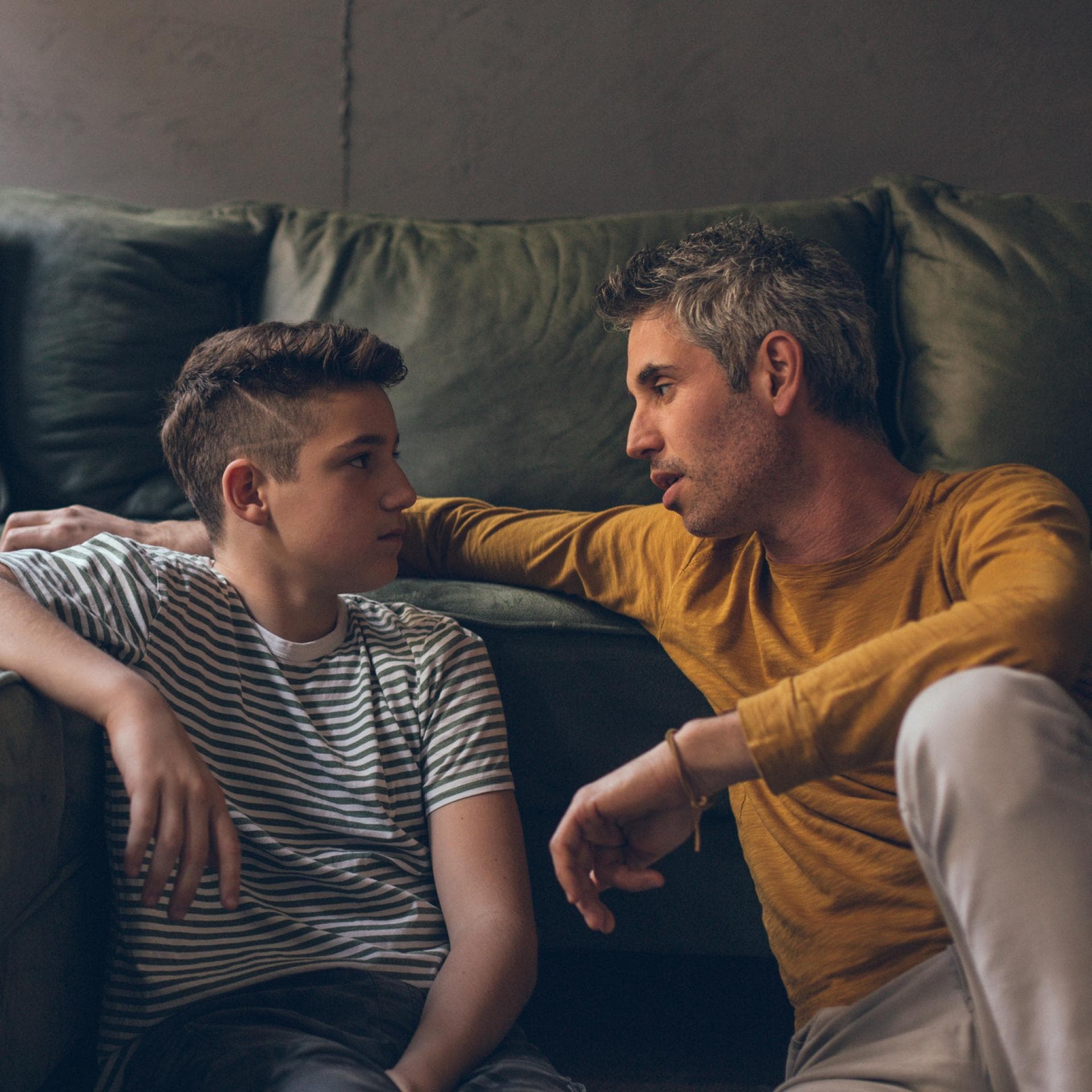 Vater unterhält sich mit jugendlichem Sohn.