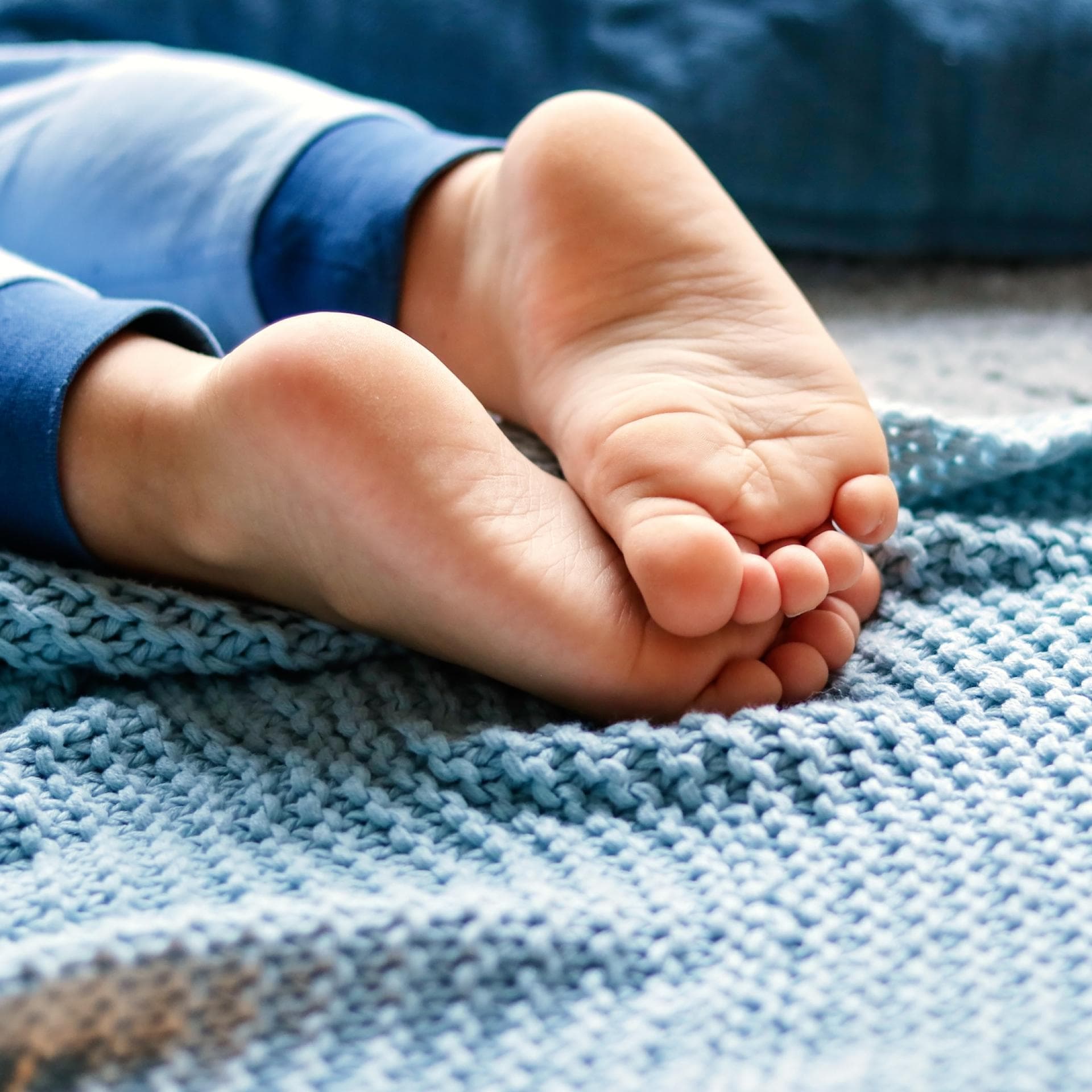 Nahaufnahme von barfüßigen Kinderfüßen auf blauer Decke