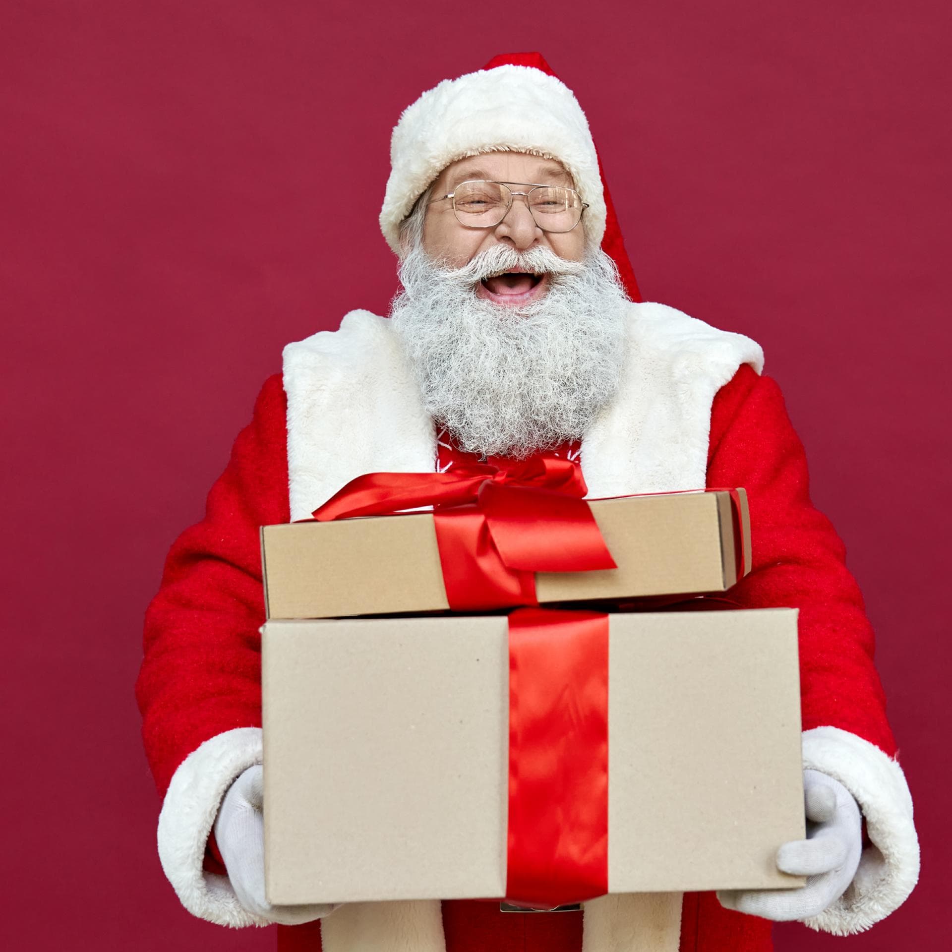 Ein Nikolaus mit Geschenken im Arm lacht aus vollem Herzen. 