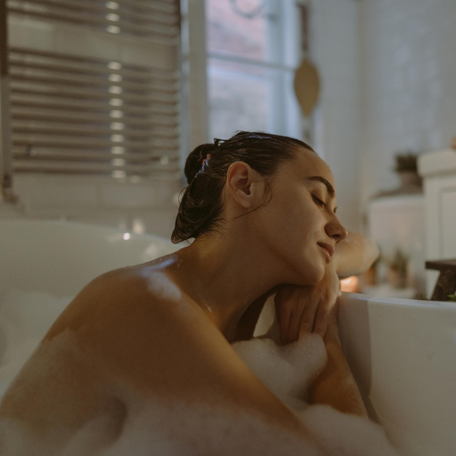 Eine Frau, die in der Badewanne sitzt und die Augen schließt. 