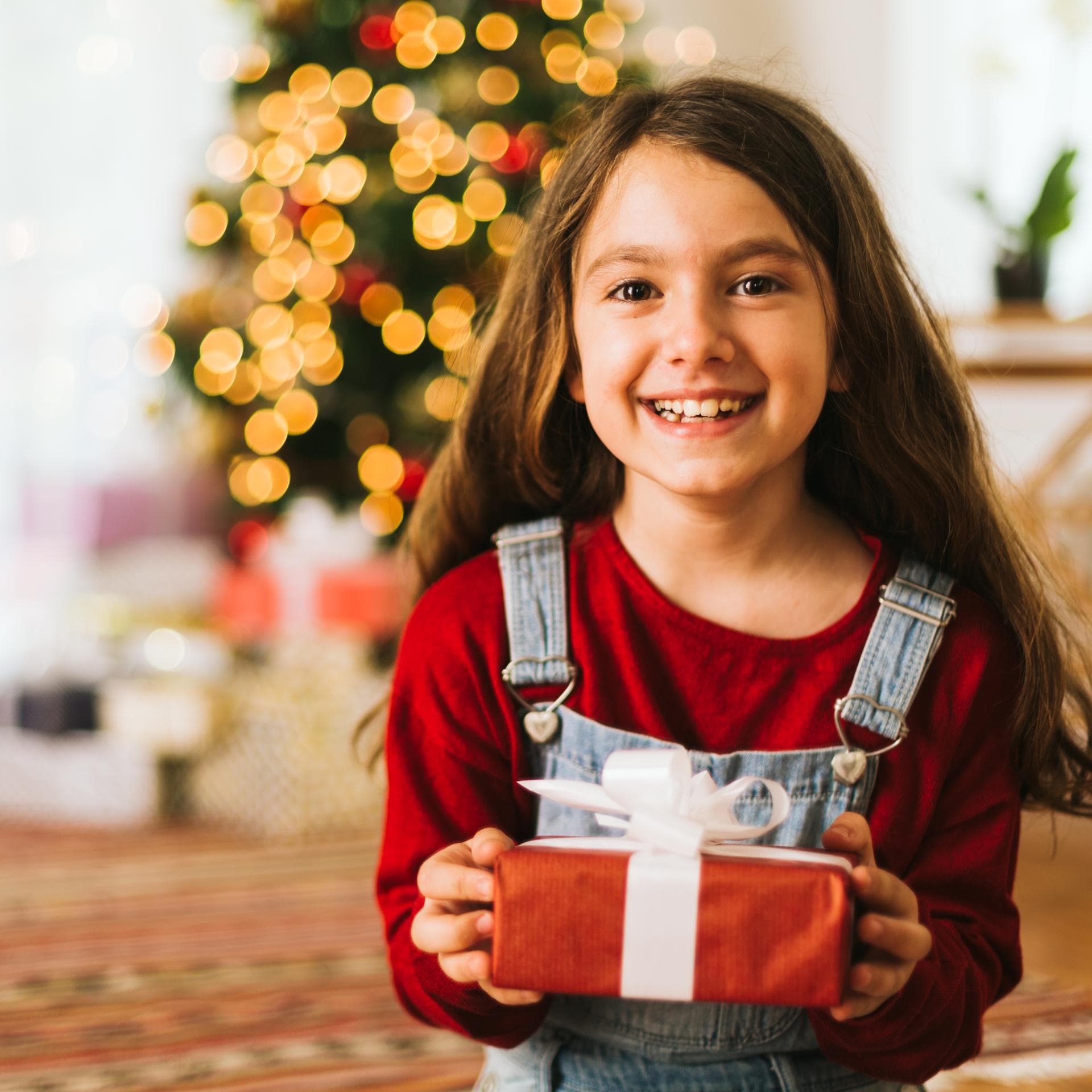 Lachendes Mädchen übergibt Weihnachtsgeschenk.