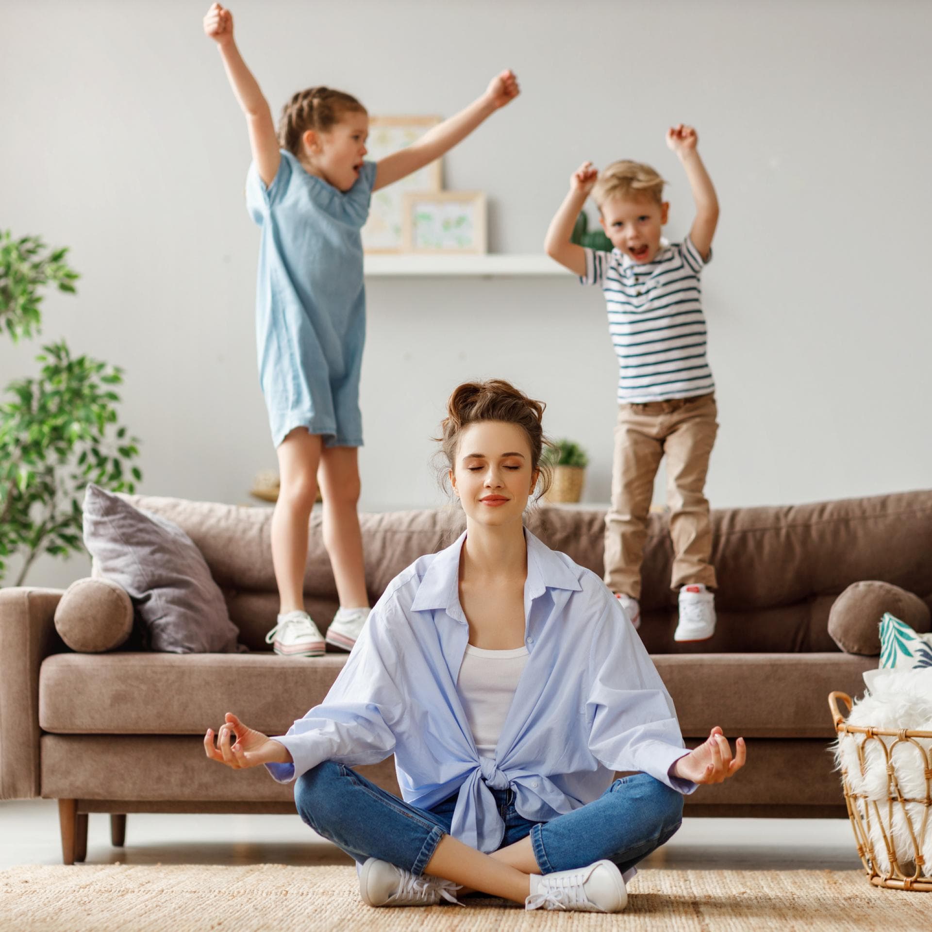Kinder springen auf dem Sofa, Mutter meditiert.