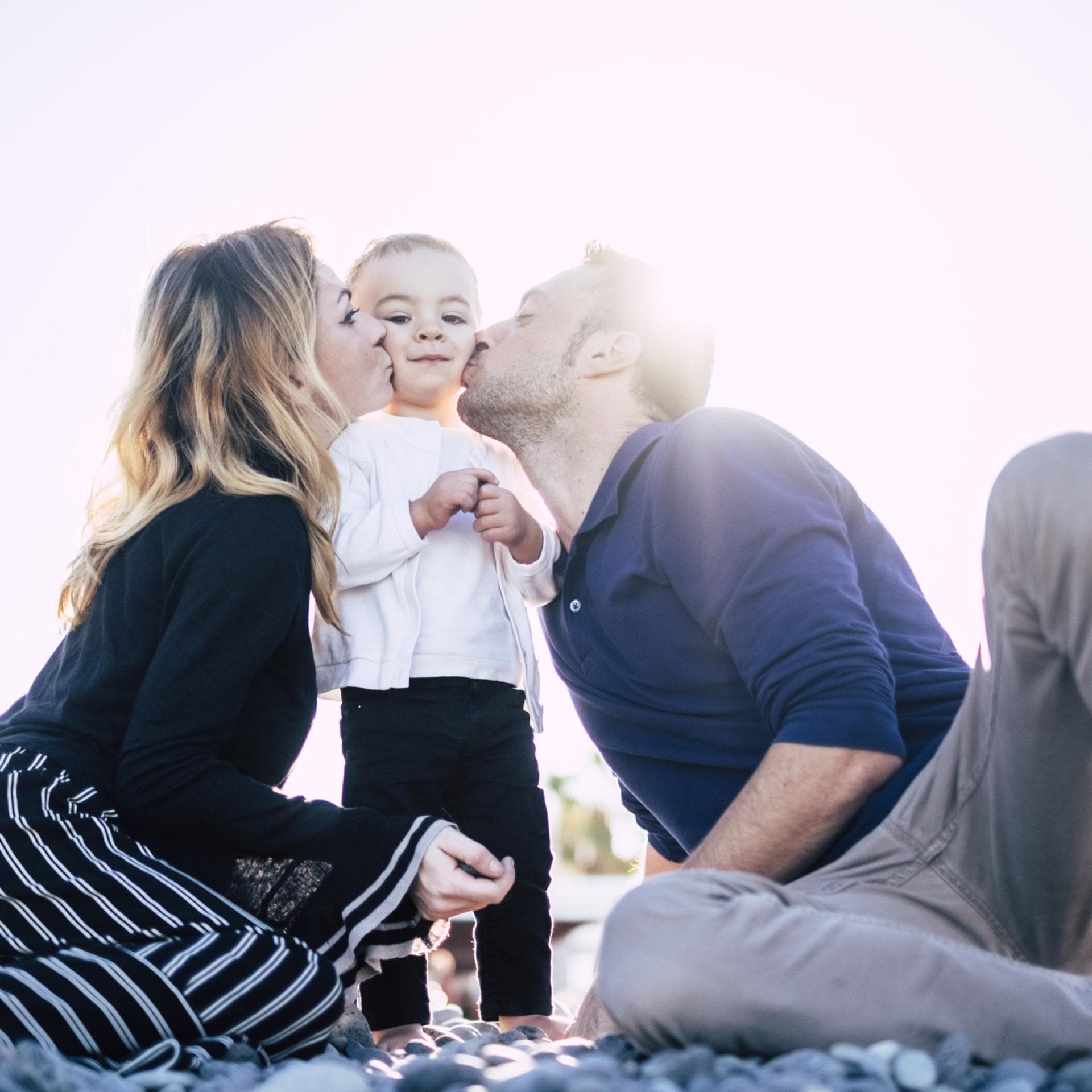 Eltern umringen ihr Kind und küssen es.
