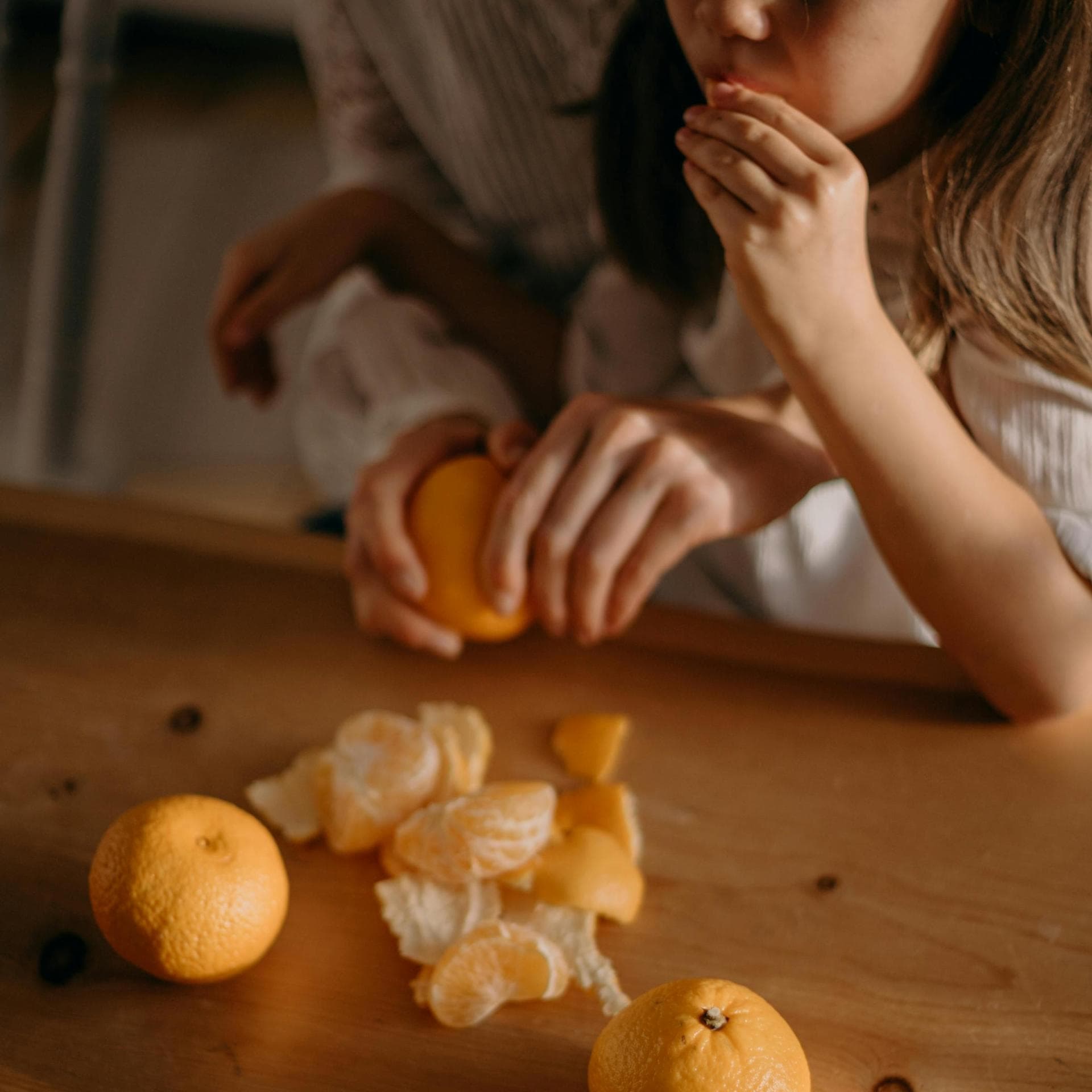 Mädchen isst Mandarine, Mutter schält sie.