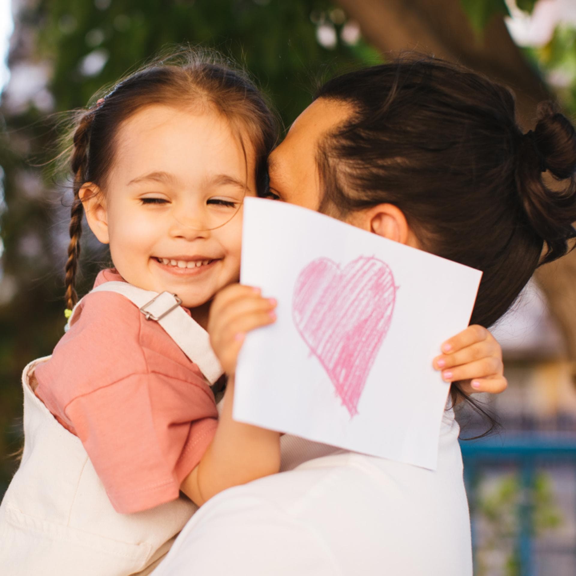 Ein Mädchen mit einer Postkarte in der Hand auf dem Arm ihres Vaters. 