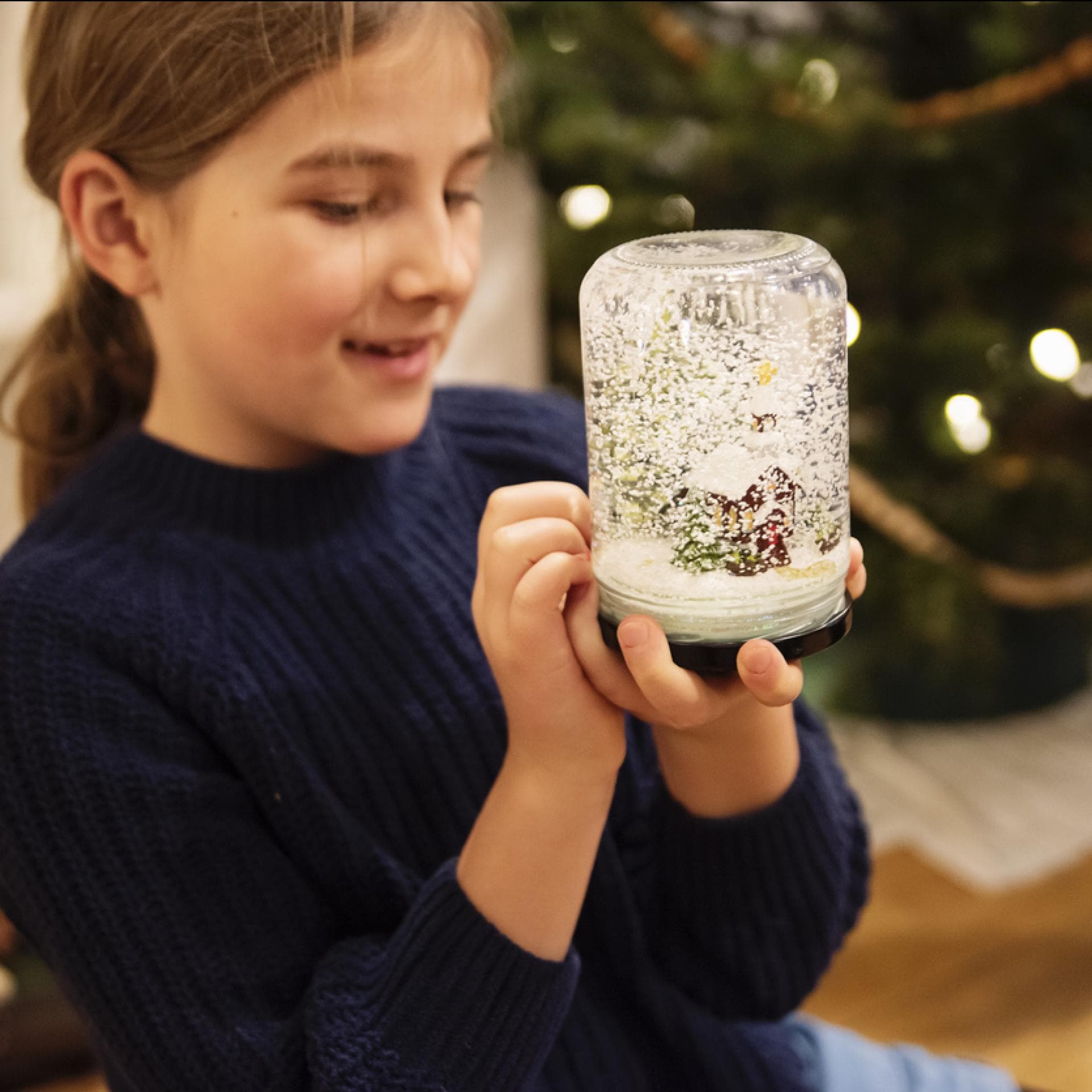 Mädchen hält selbstgebastelte Schneekugel in der Hand.
