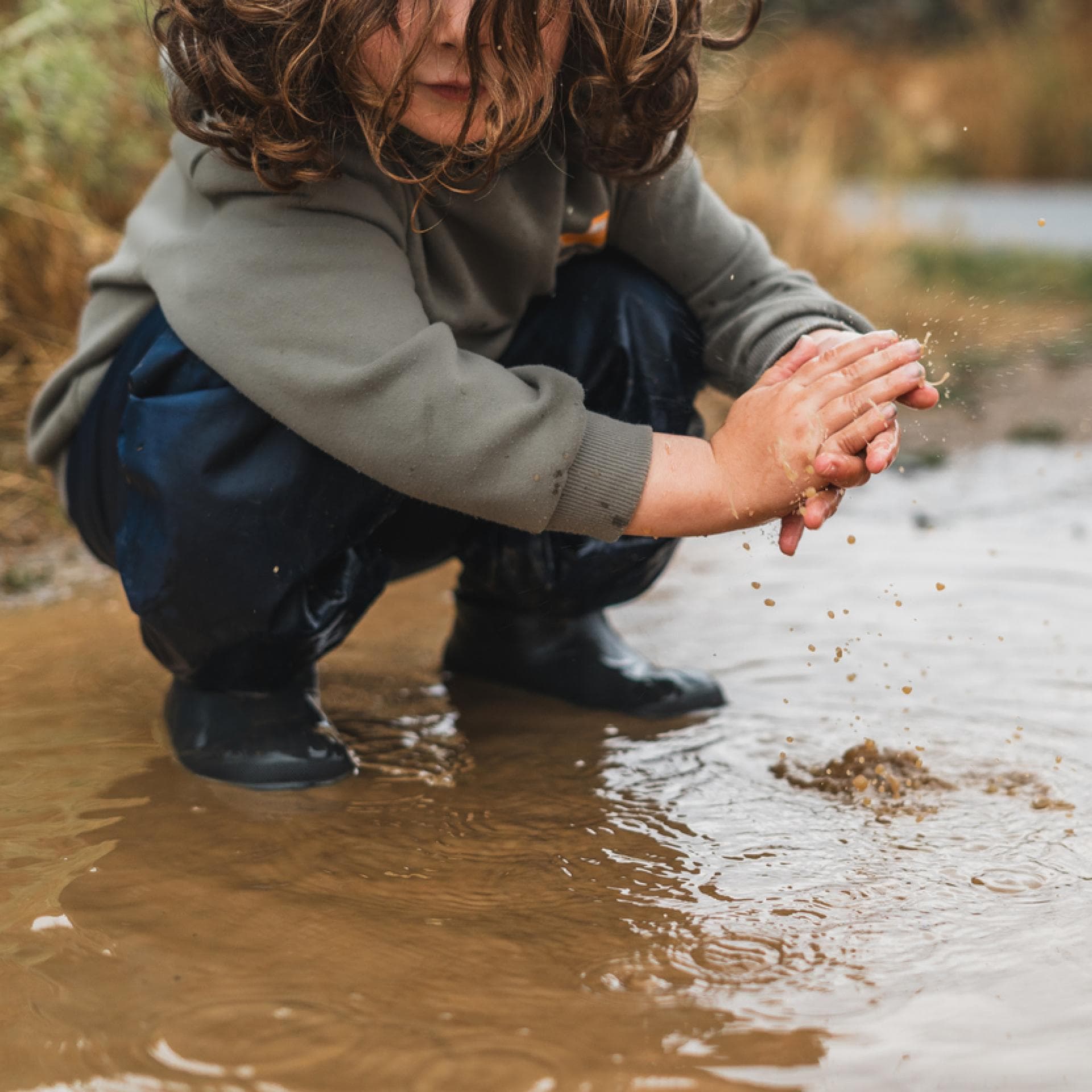 Kind spielt in einer Pfütze