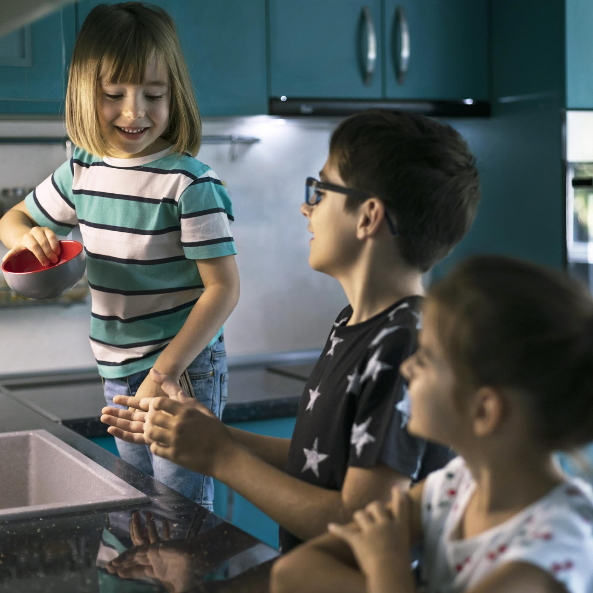 Drei Kinder am Spülbecken.