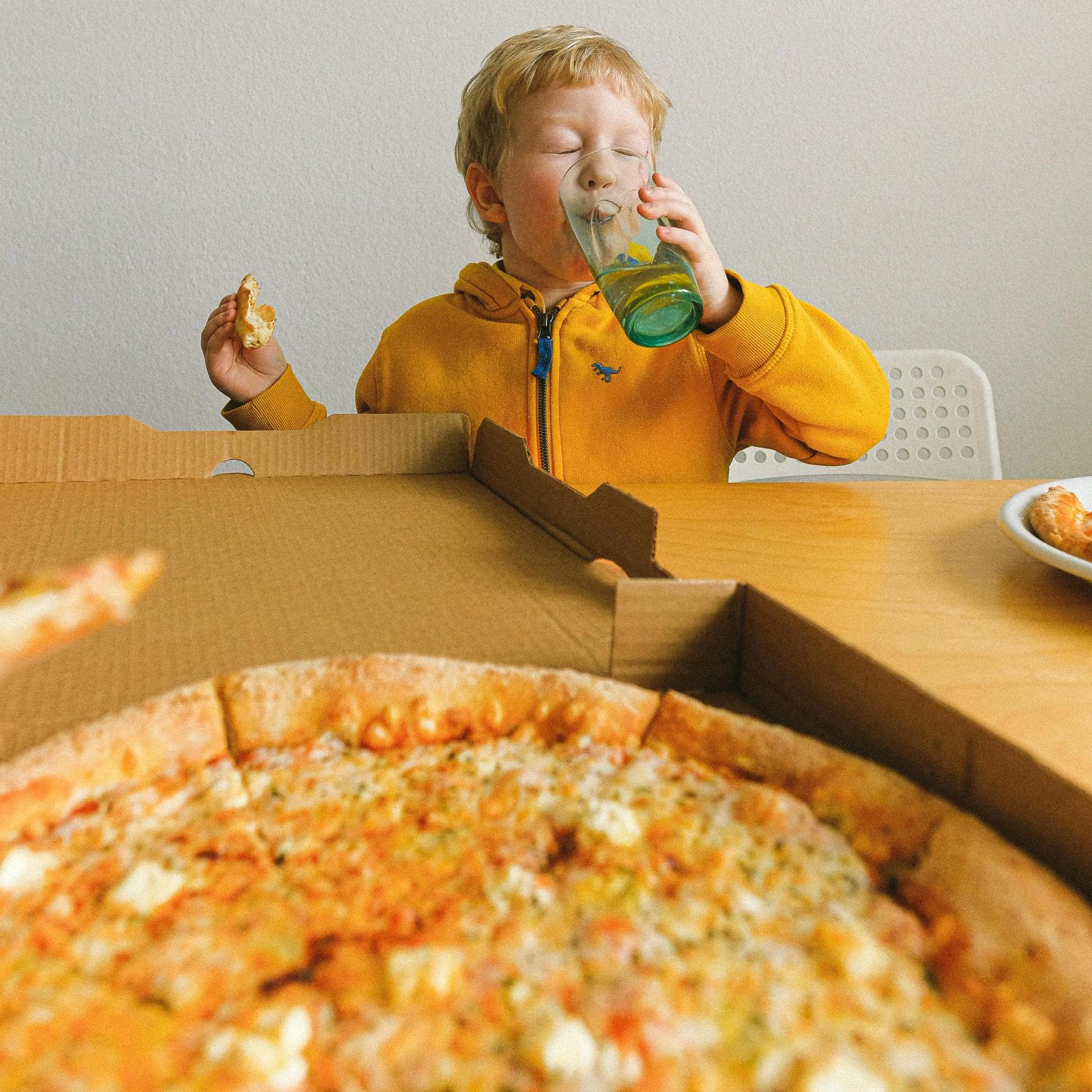 Kind isst Pizza aus Karton