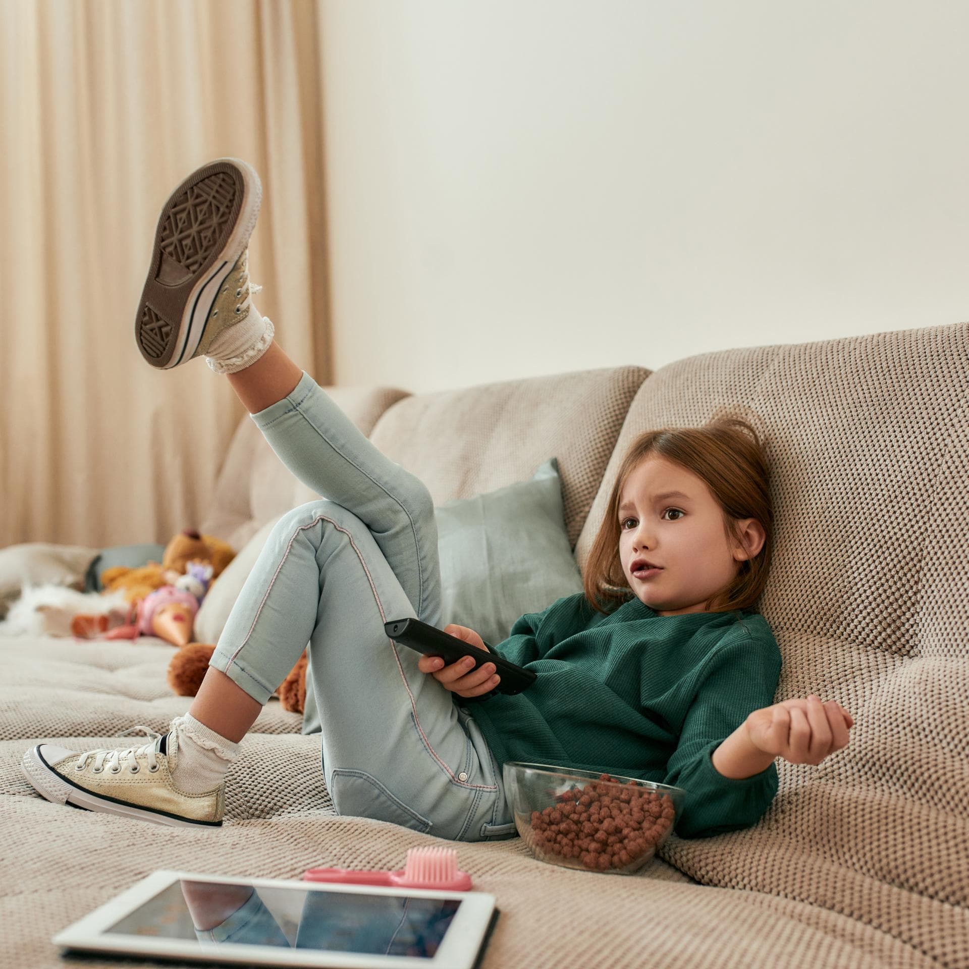 Mädchen auf dem Sofa vorm Fernseher.