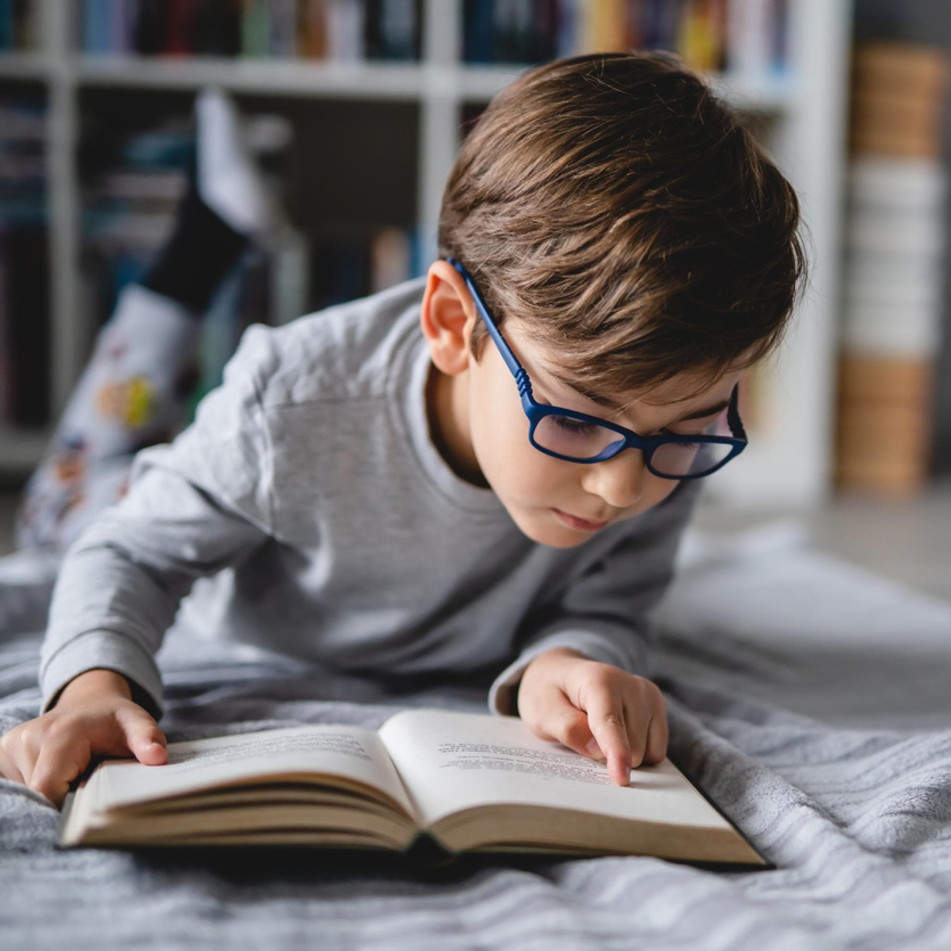 Junge, der auf dem Boden liegt und ein Buch liest.