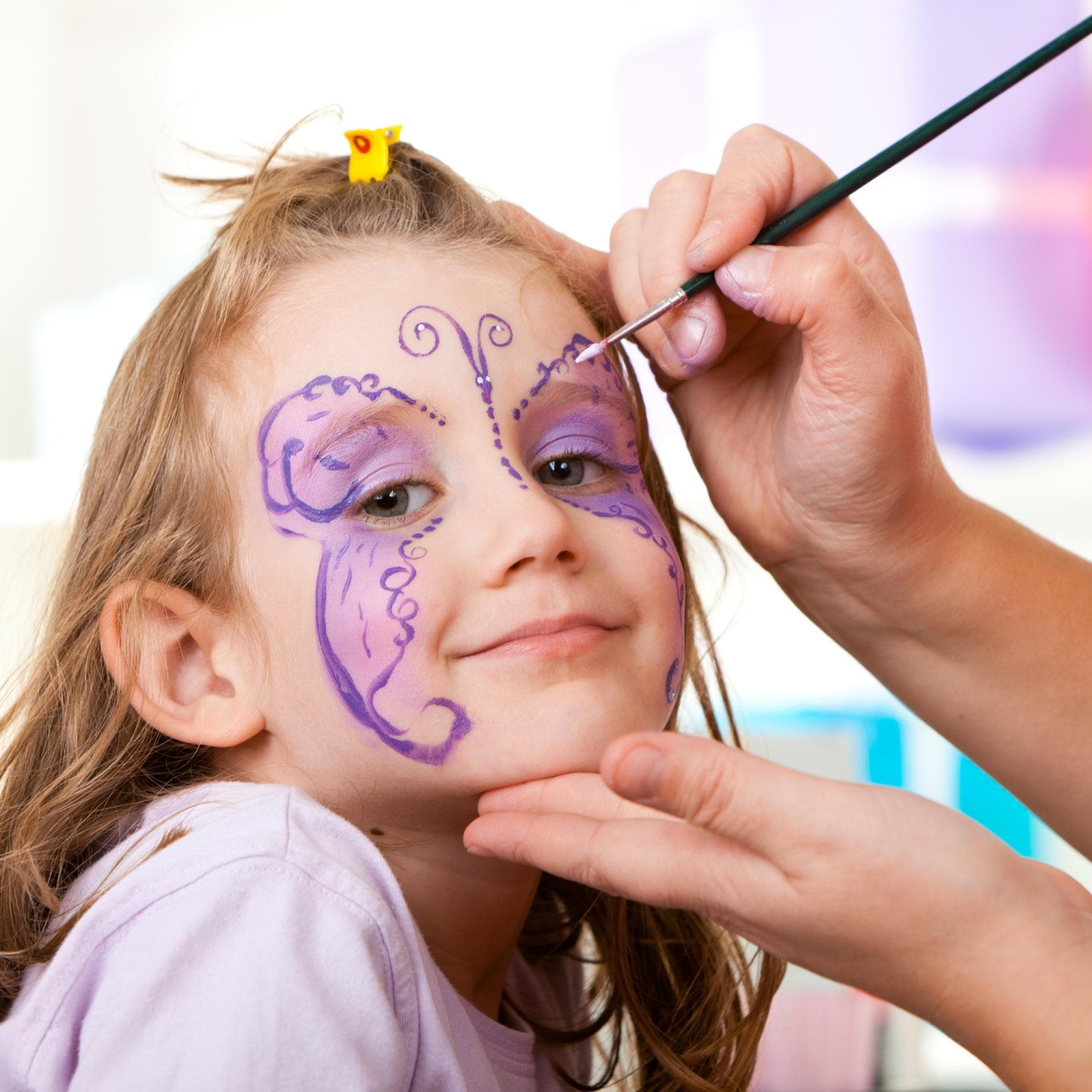 Mädchen wird als Schmetterling geschminkt.